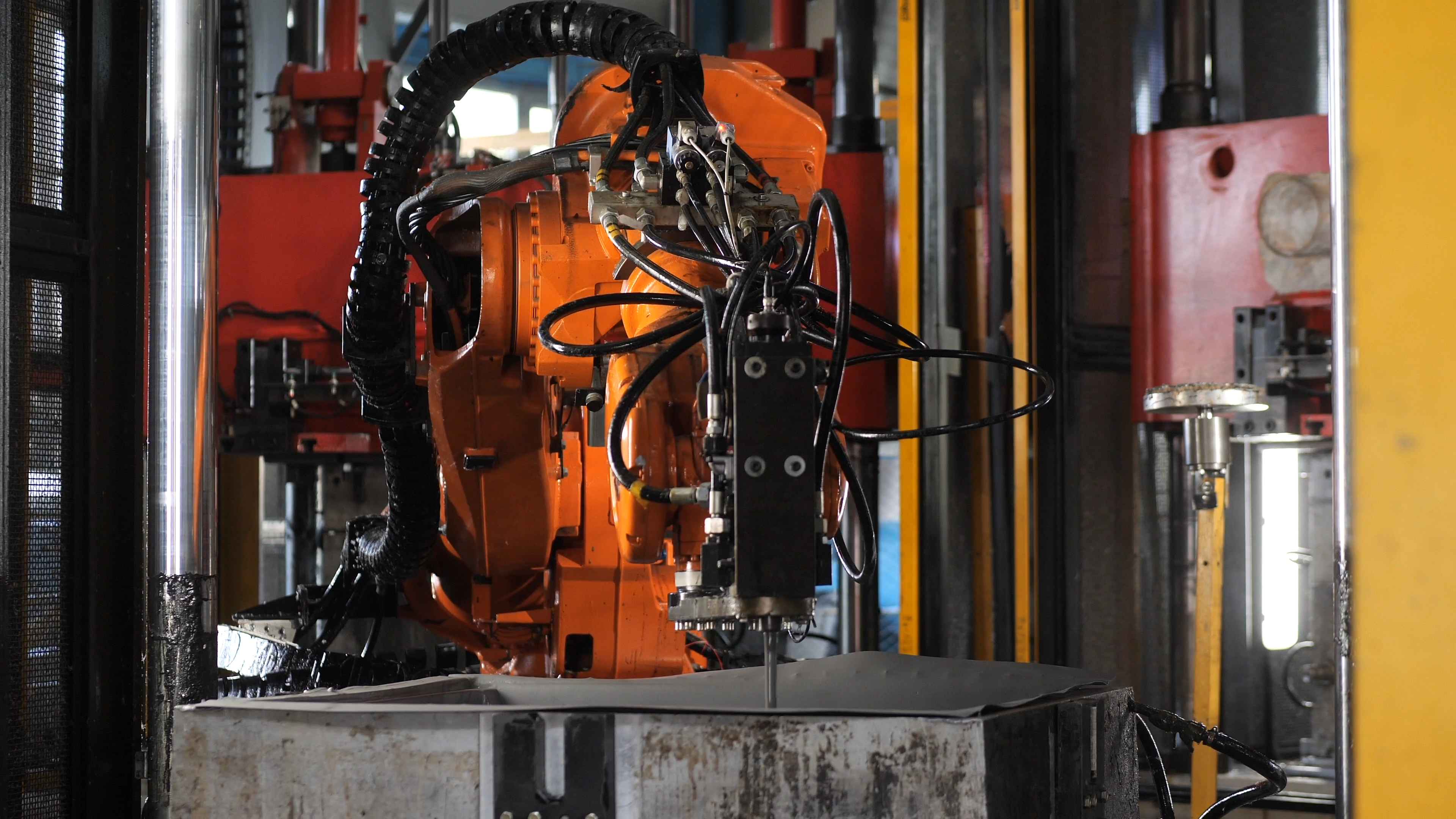 Orange industrial robot arm over a metal press