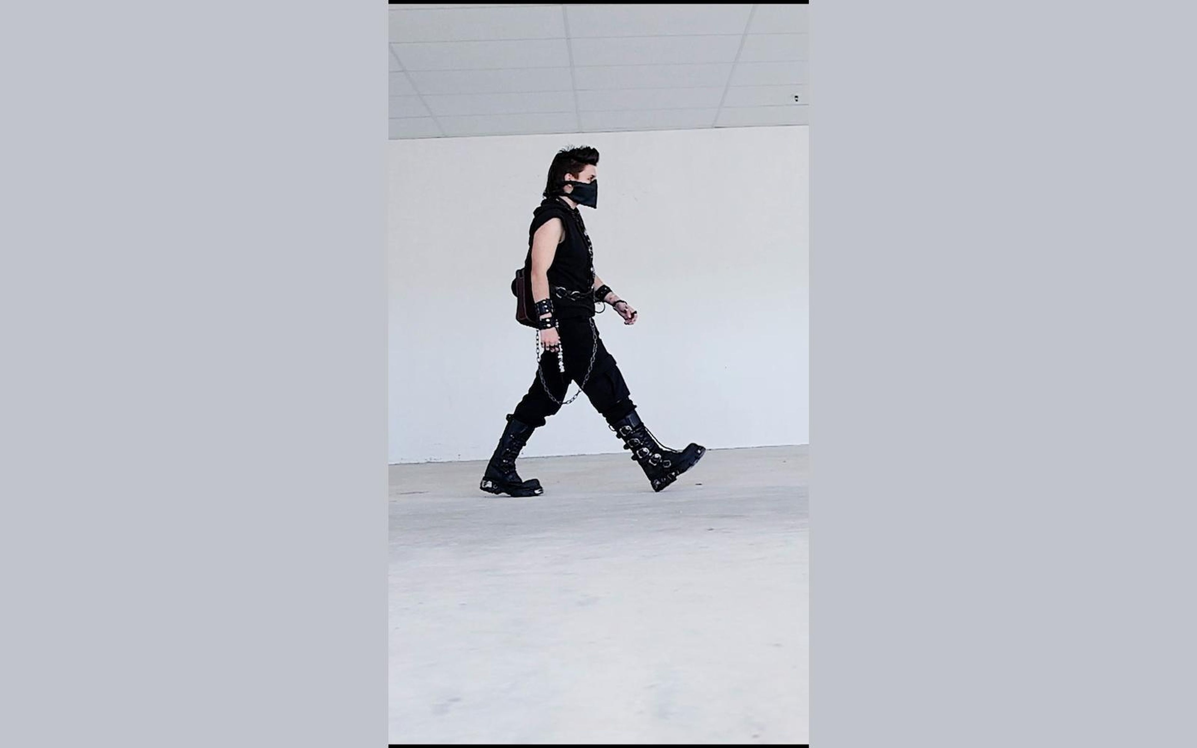 Wide stride in profile with buckled boots stretched across a white floor