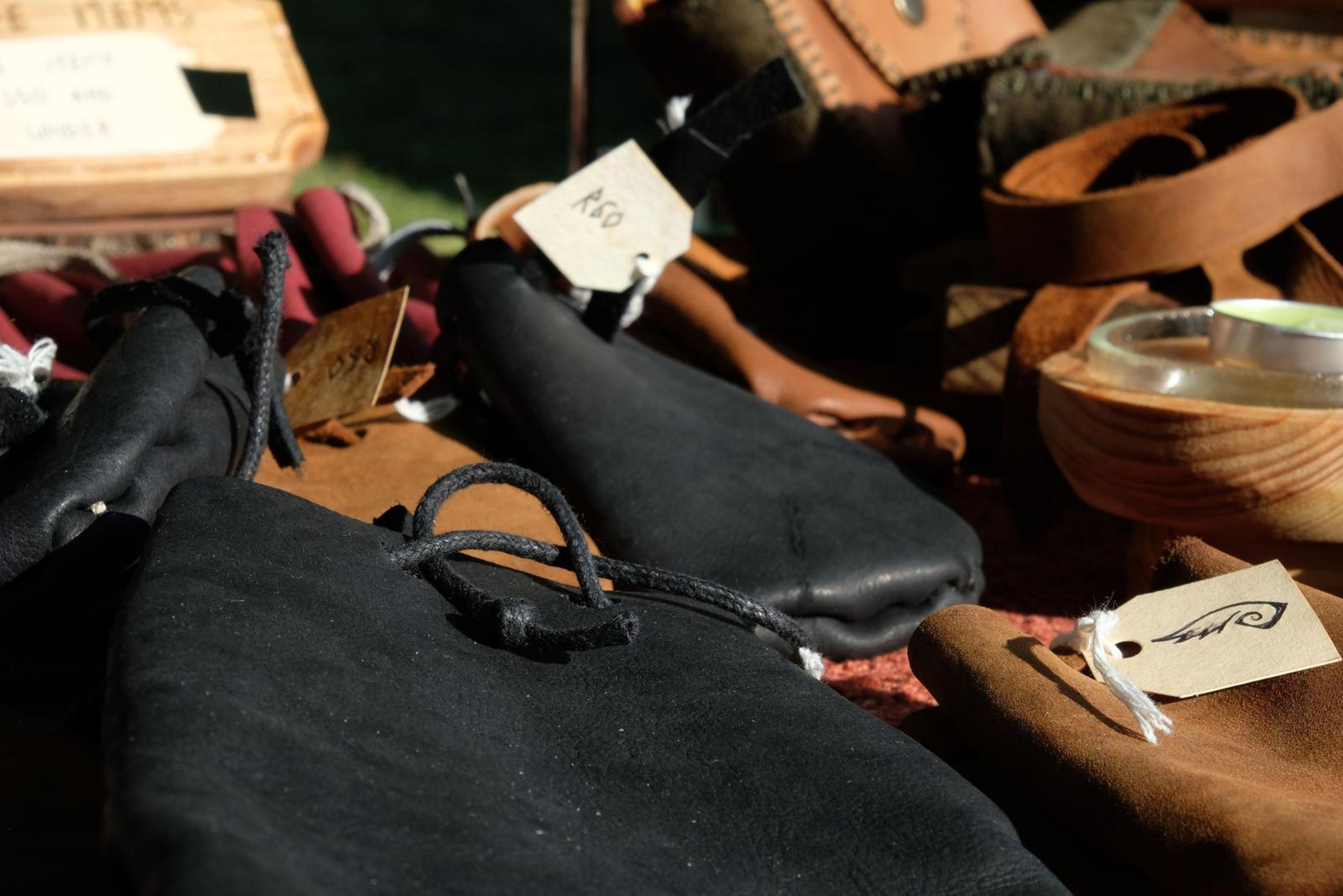 Black and tan leather pouches with handwritten tags piled on the table