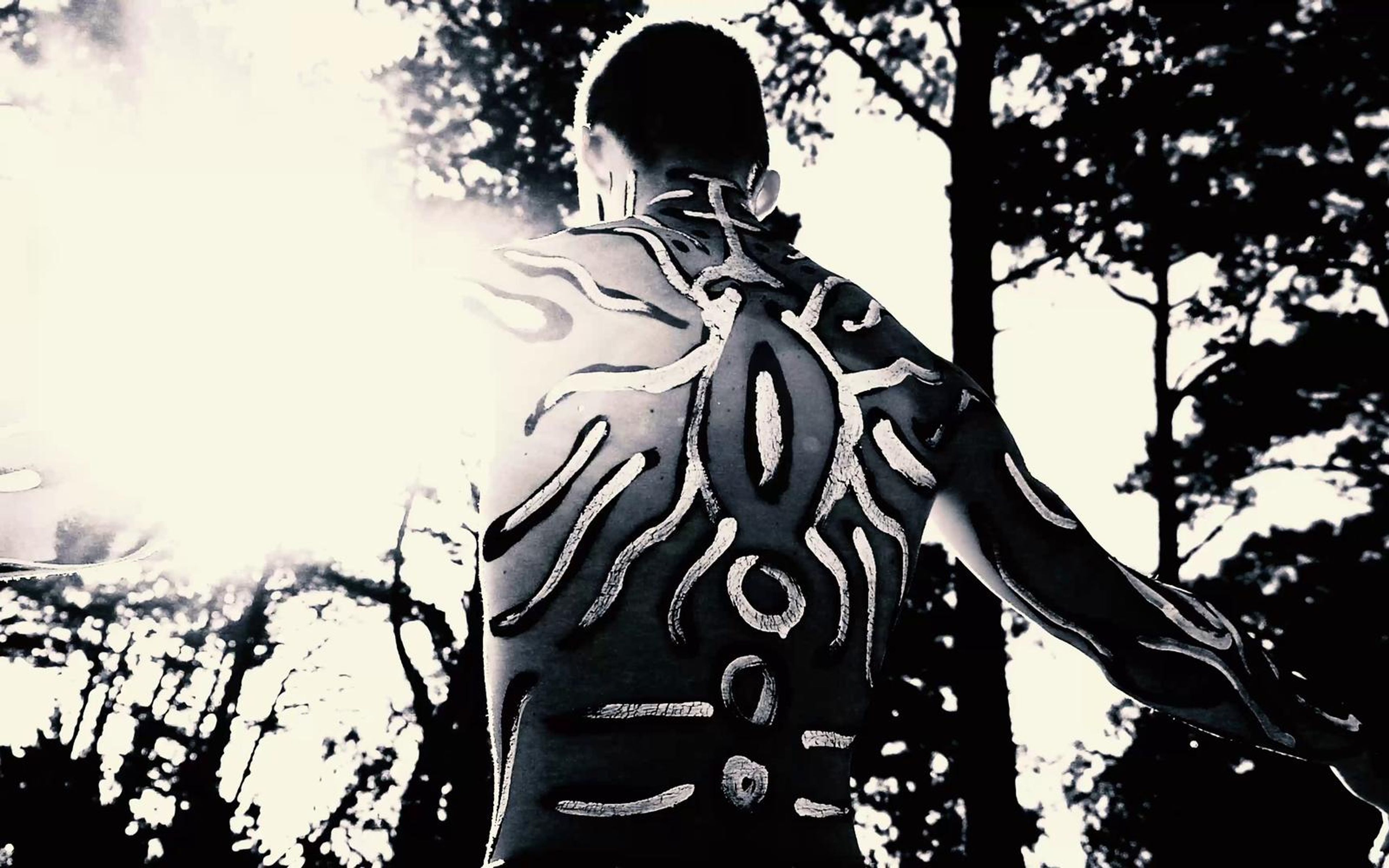 Performer from behind in black and white painted patterns against blown-out sky