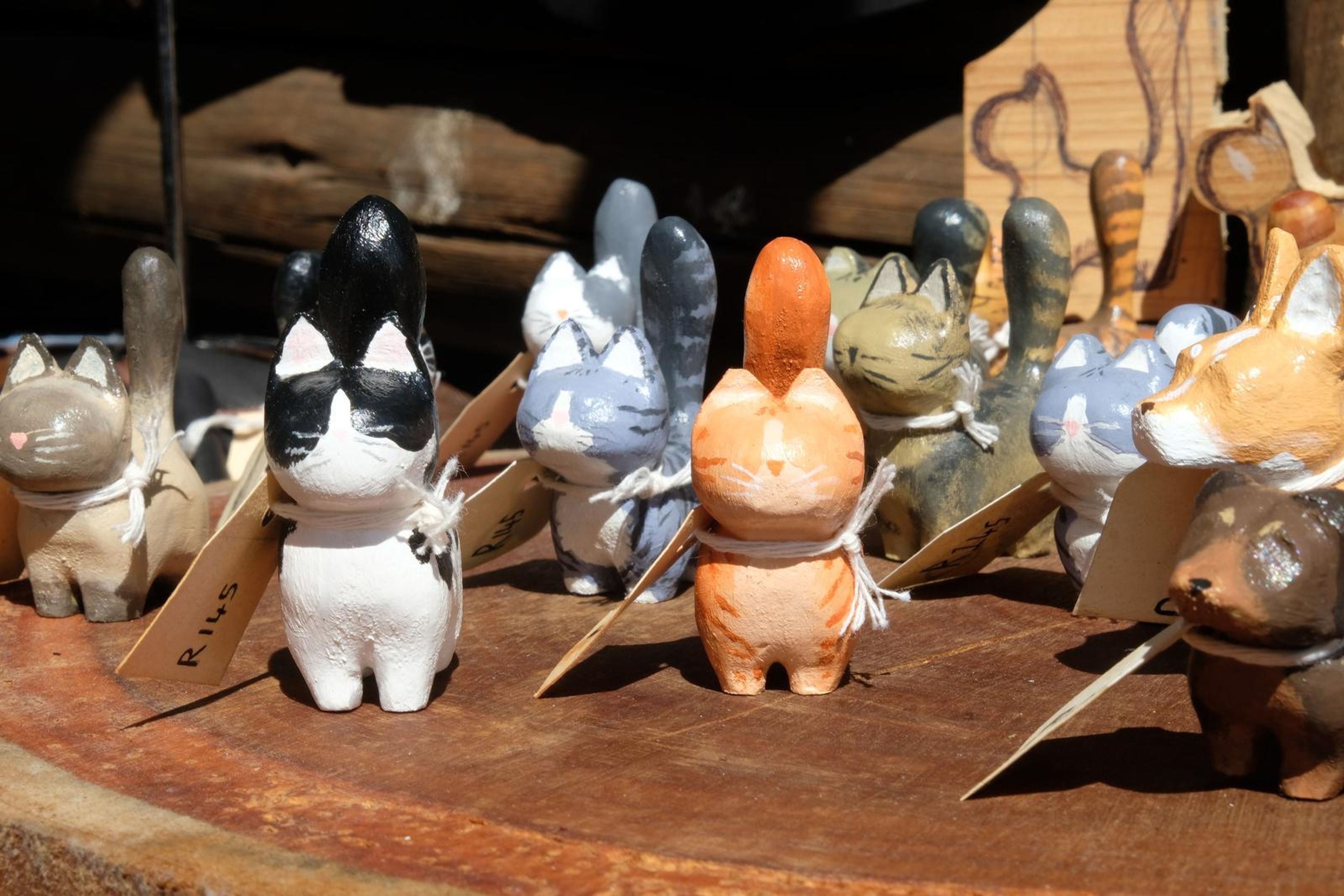 Hand-painted carved wooden cat figures with handwritten tags