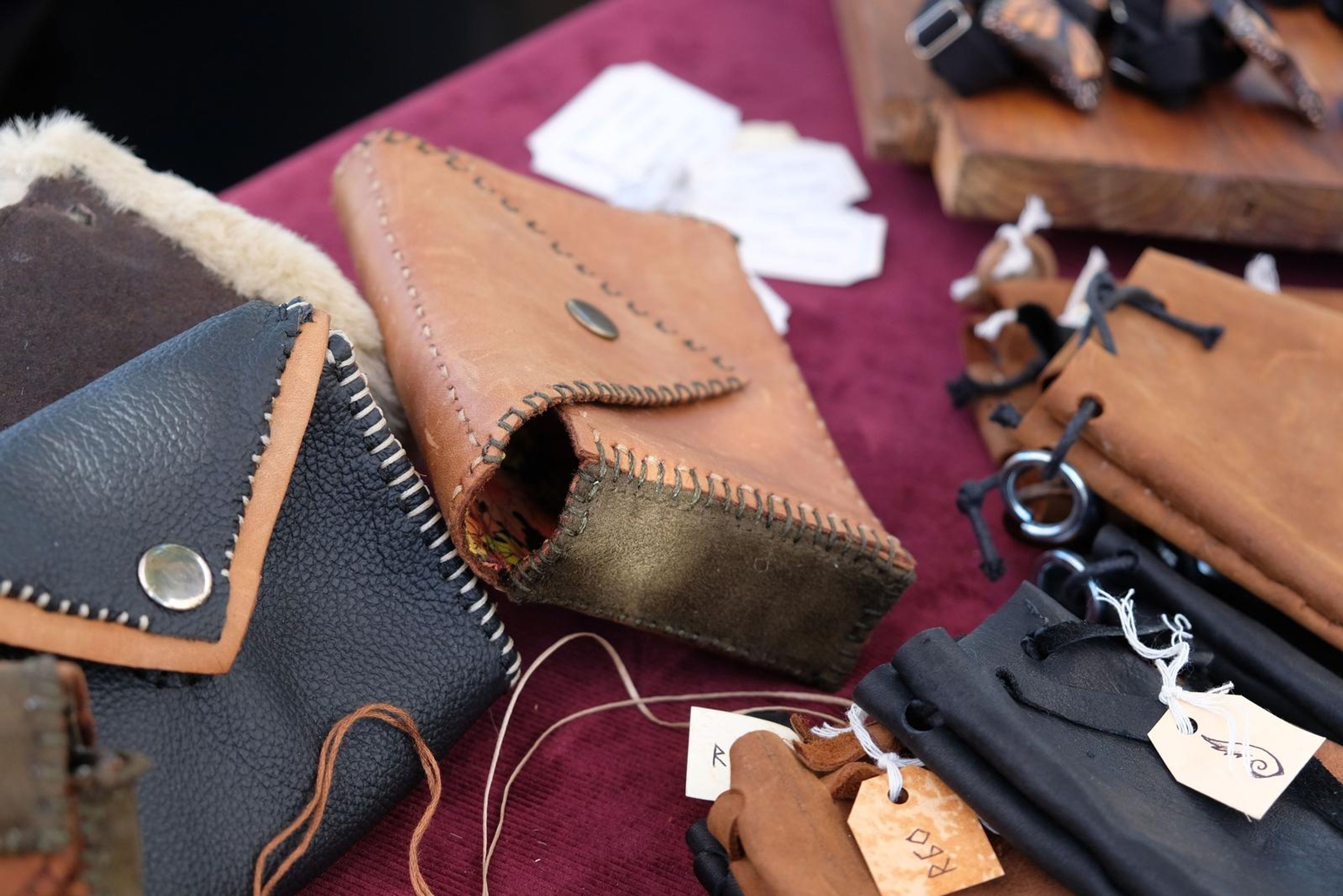 Leather wallets and wire-wrapped crystal pendants on maroon cloth