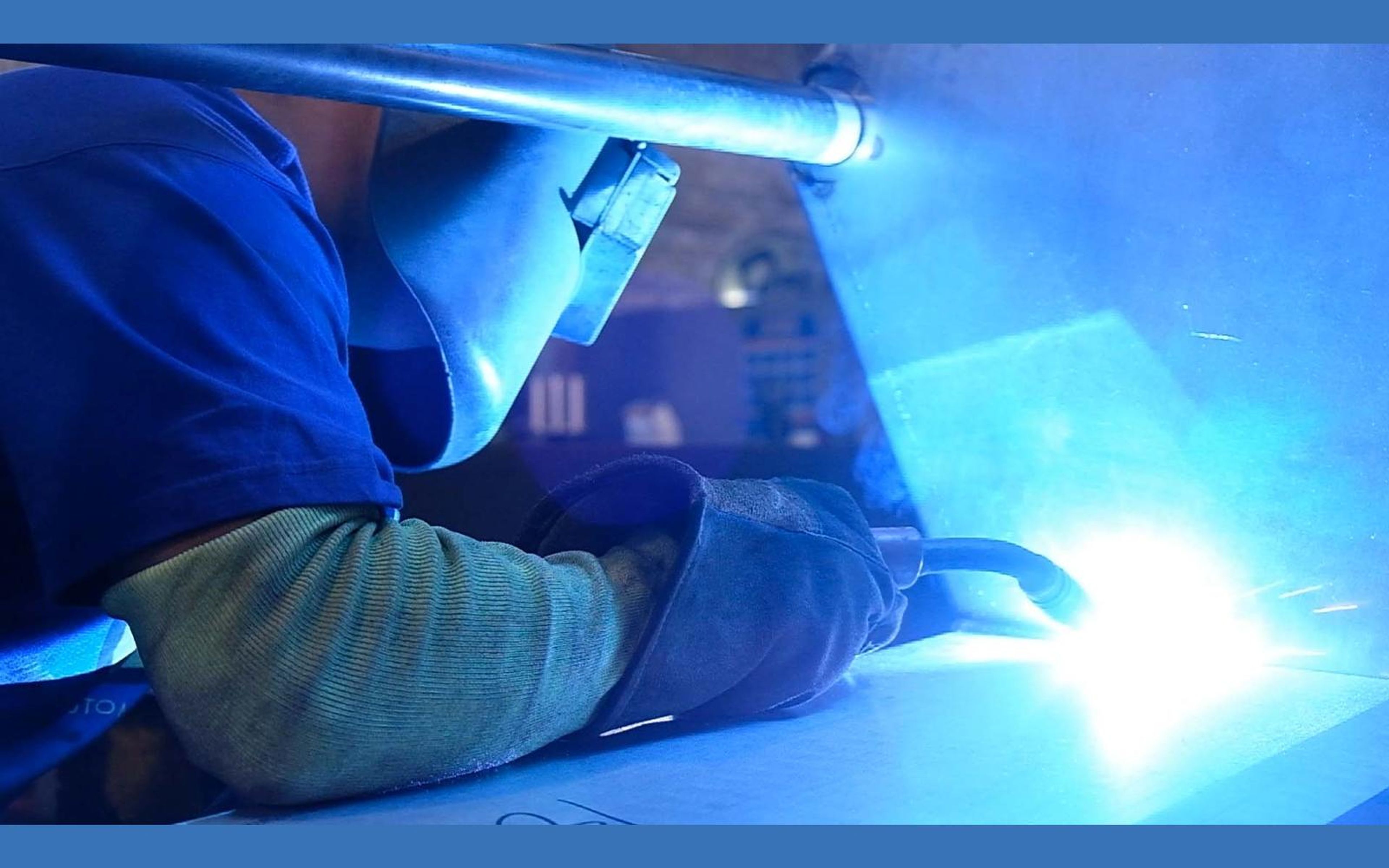 Welder in a mask working in bright blue arc light