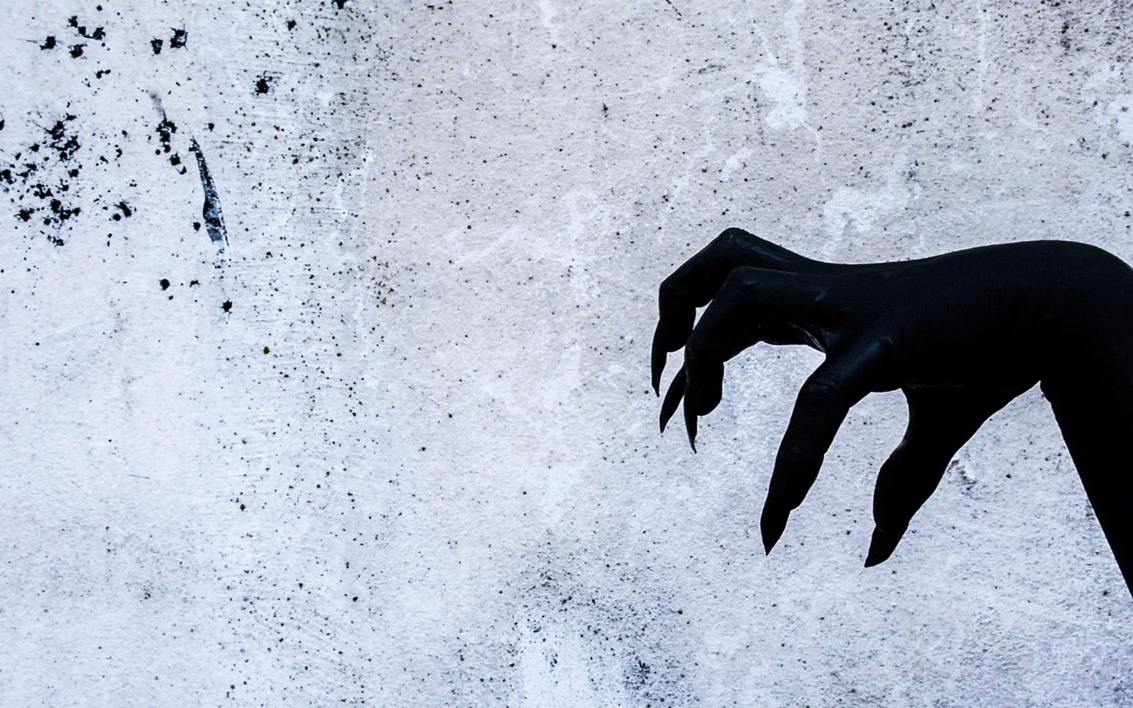 Black clawed hand reaching in from the right edge of a speckled white wall