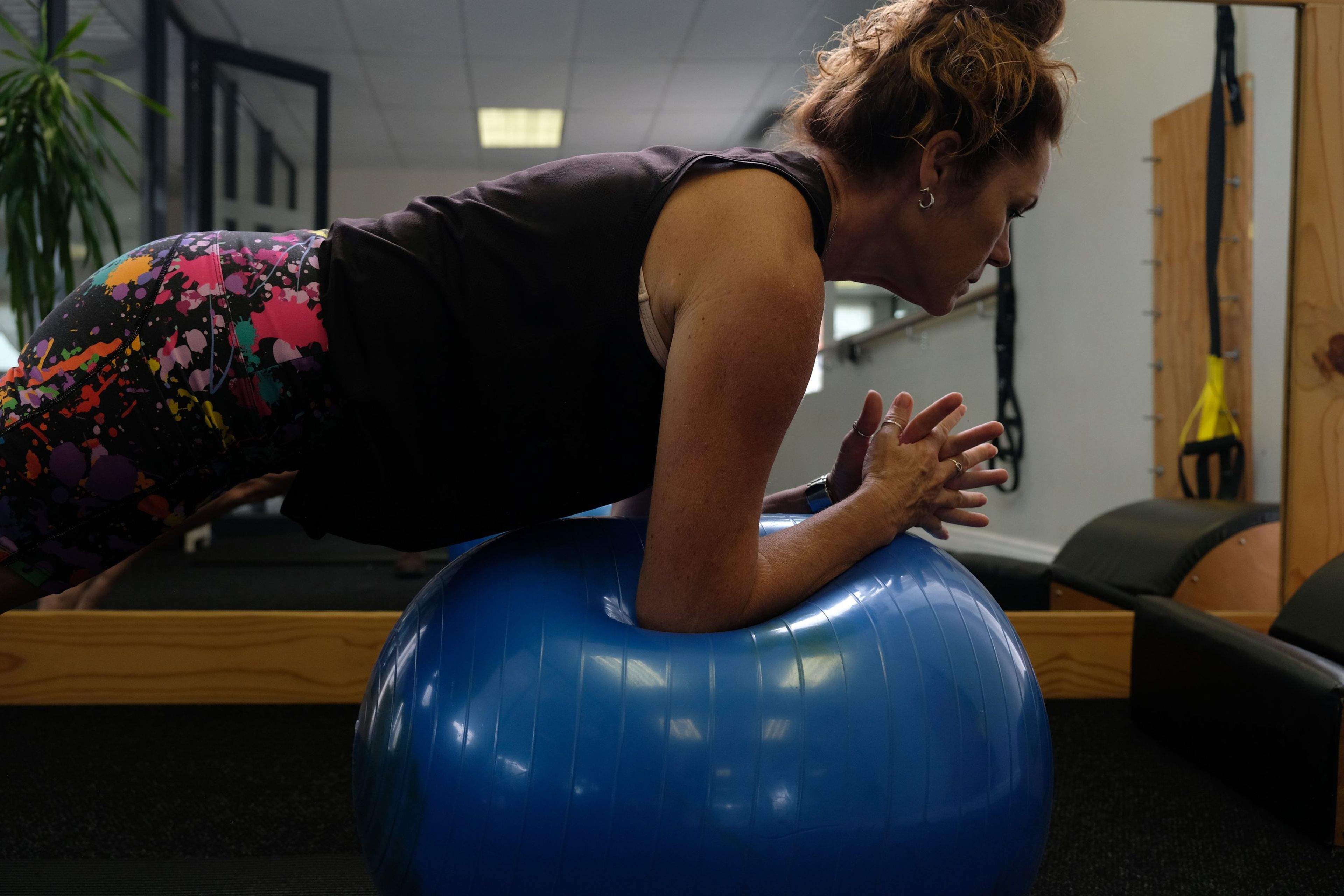 Low-angle view of an instructor in a forearm plank over a blue stability ball