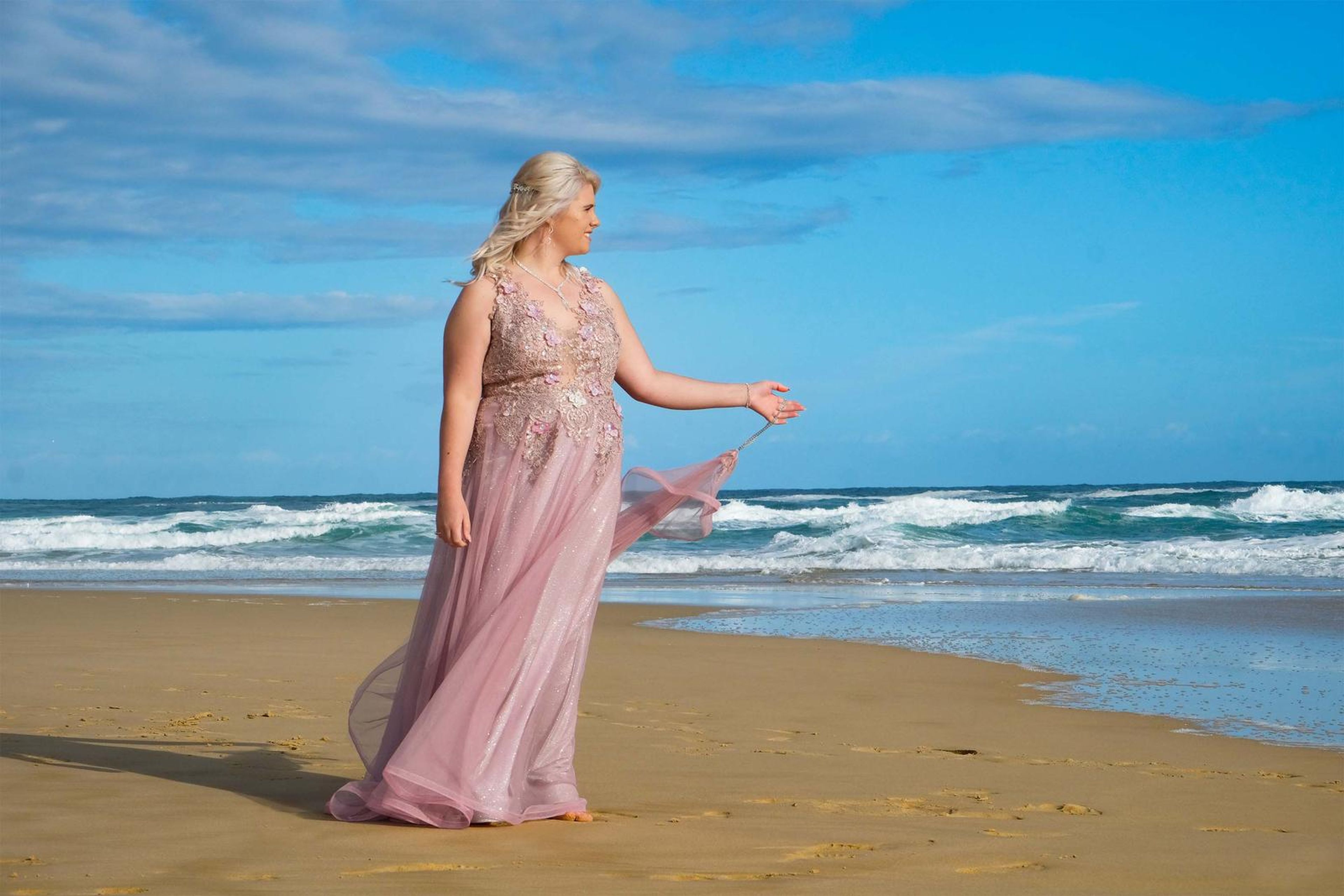 Gesturing towards the waves in the pink gown