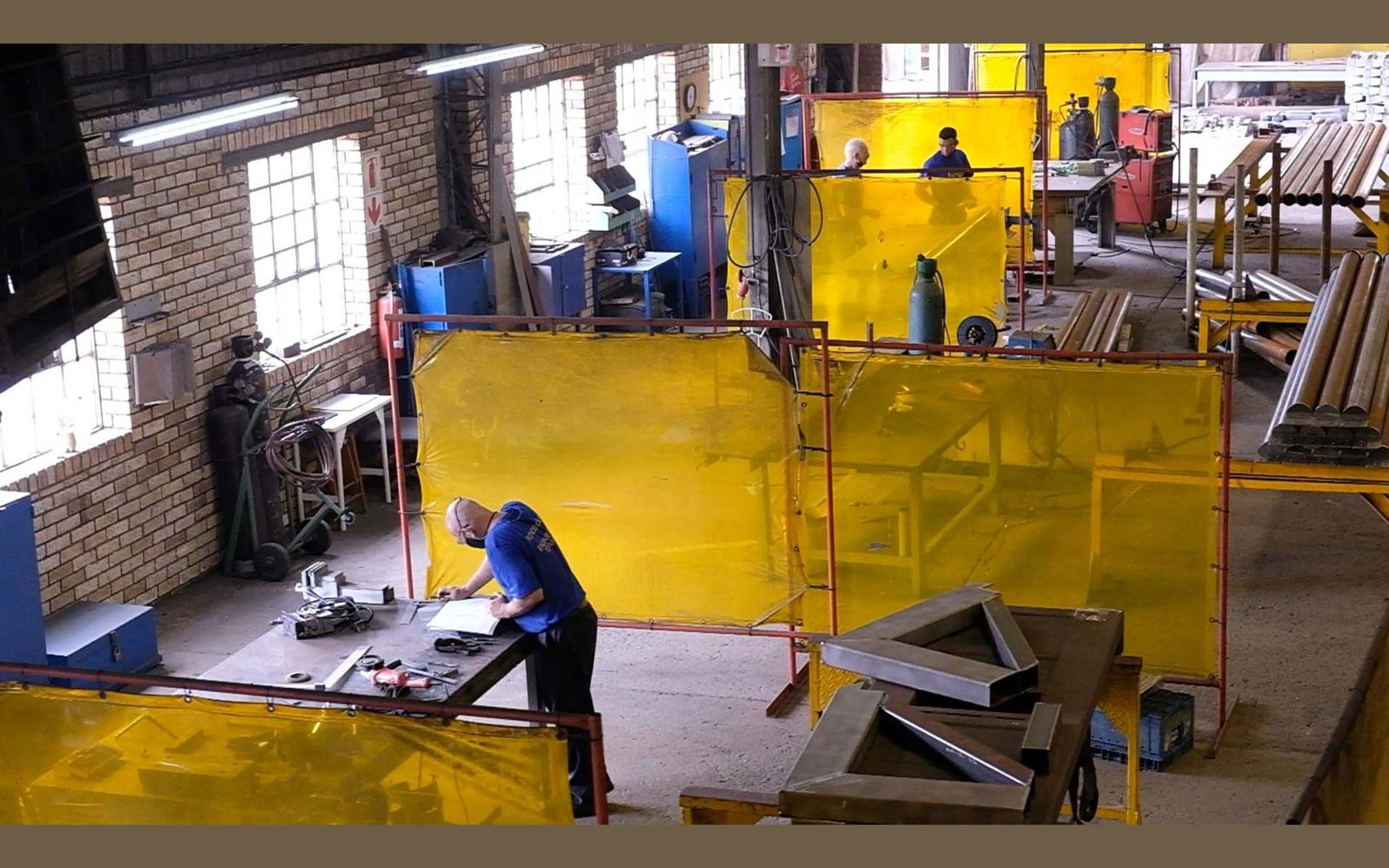 Fabricators at work among steel beams in the shop
