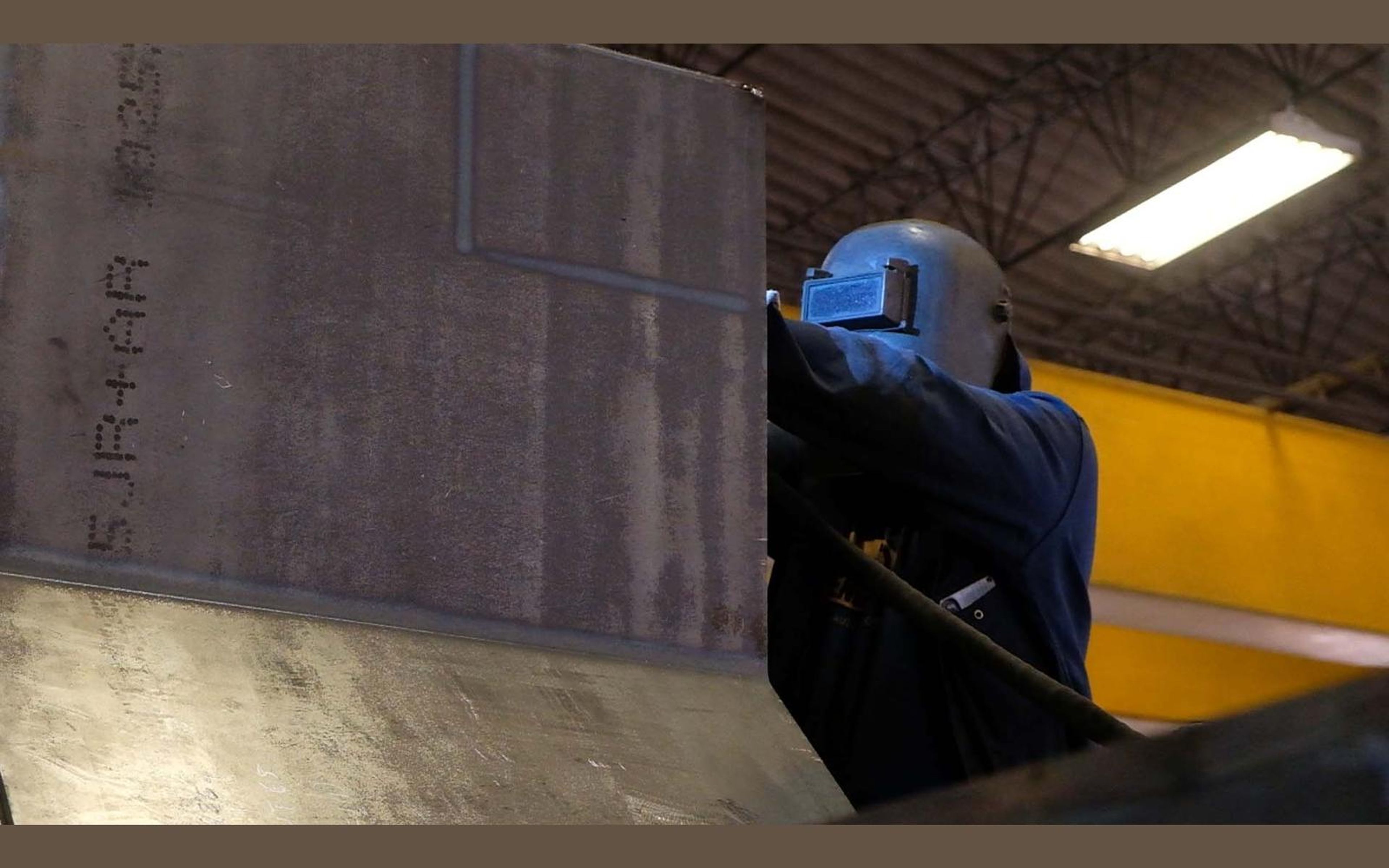 Fabrication bay with yellow welding screens and steel sections
