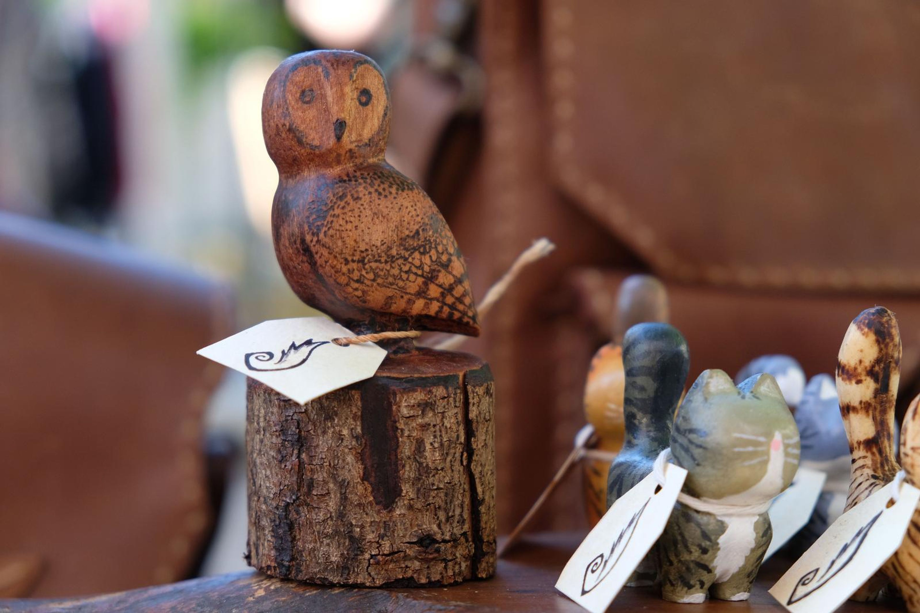 Hand-carved wooden owl on a log stand with a handwritten Juuks tag