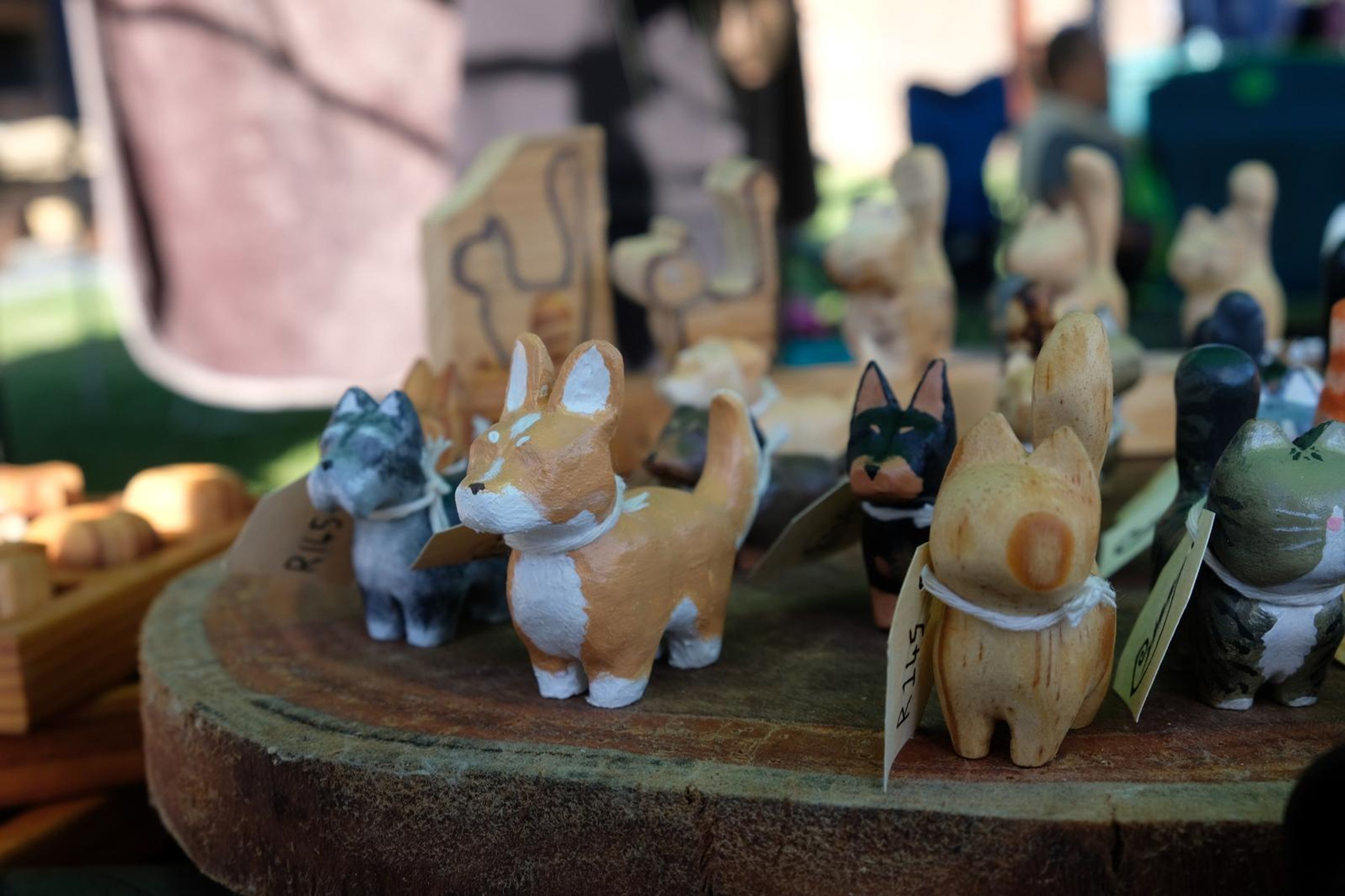 Close-up of hand-painted carved wooden pets on a bark slab