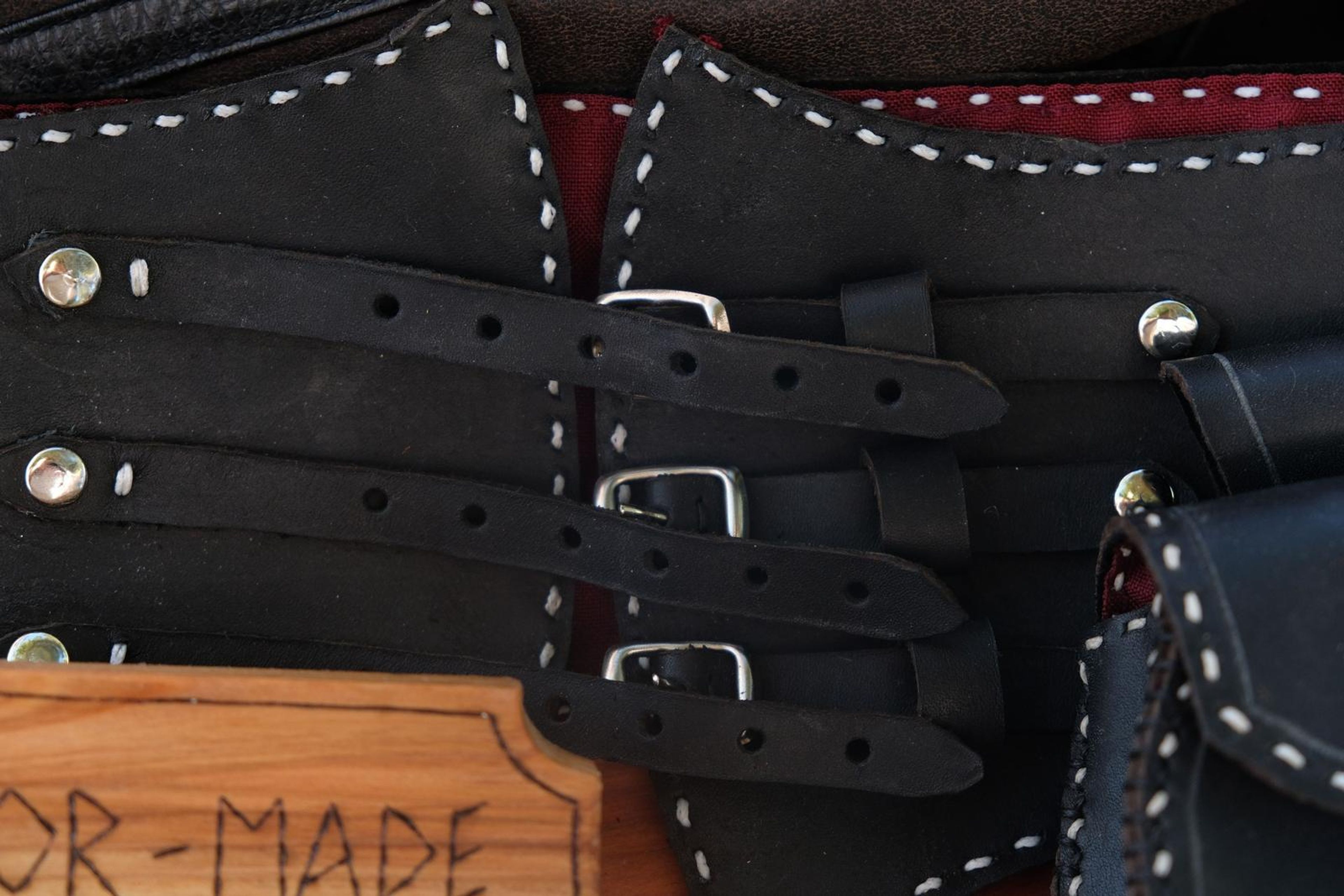 Close-up of black leather corset belt straps with silver buckles and white stitching