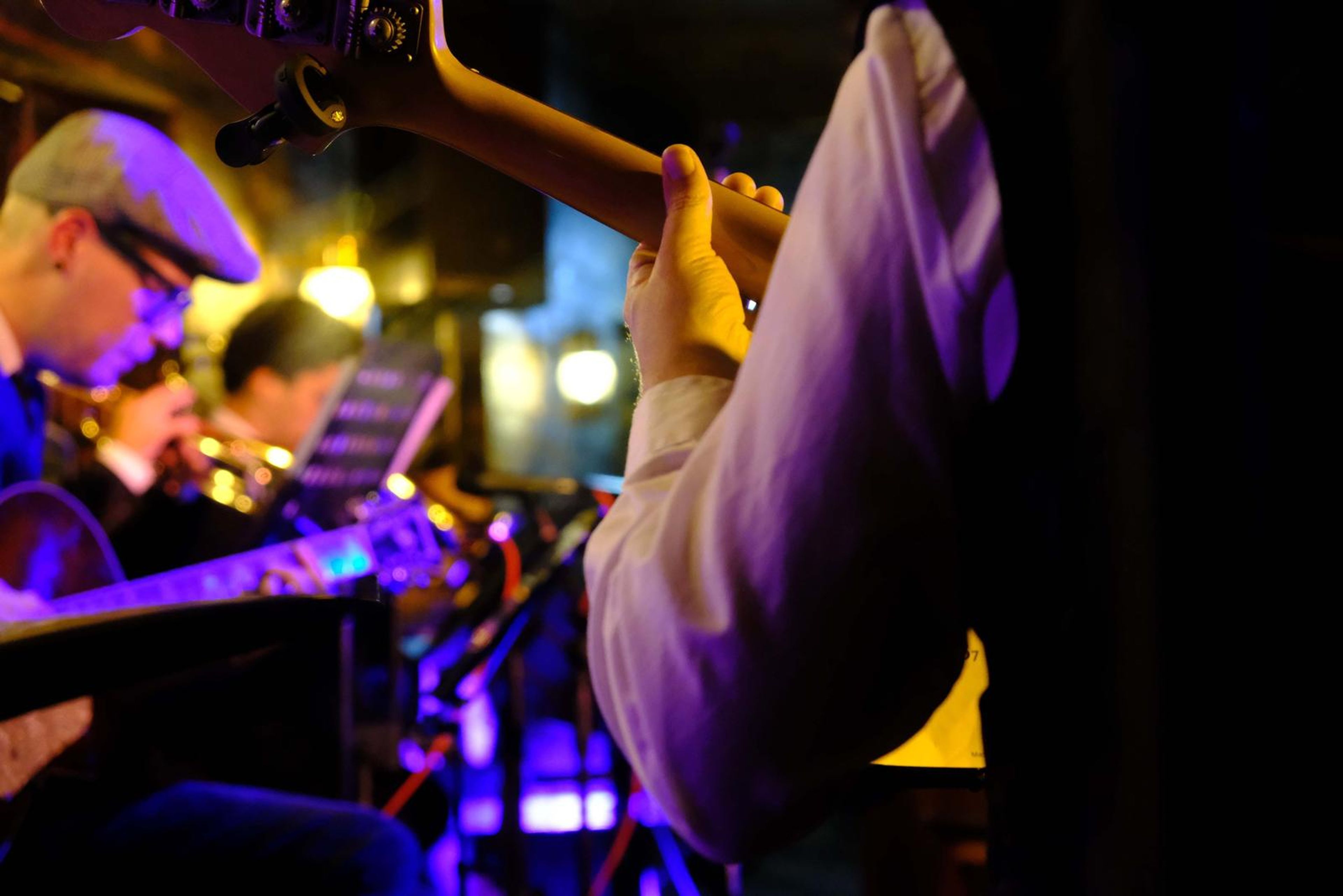 Close-up of the bass guitar neck and the bassist in a flat cap