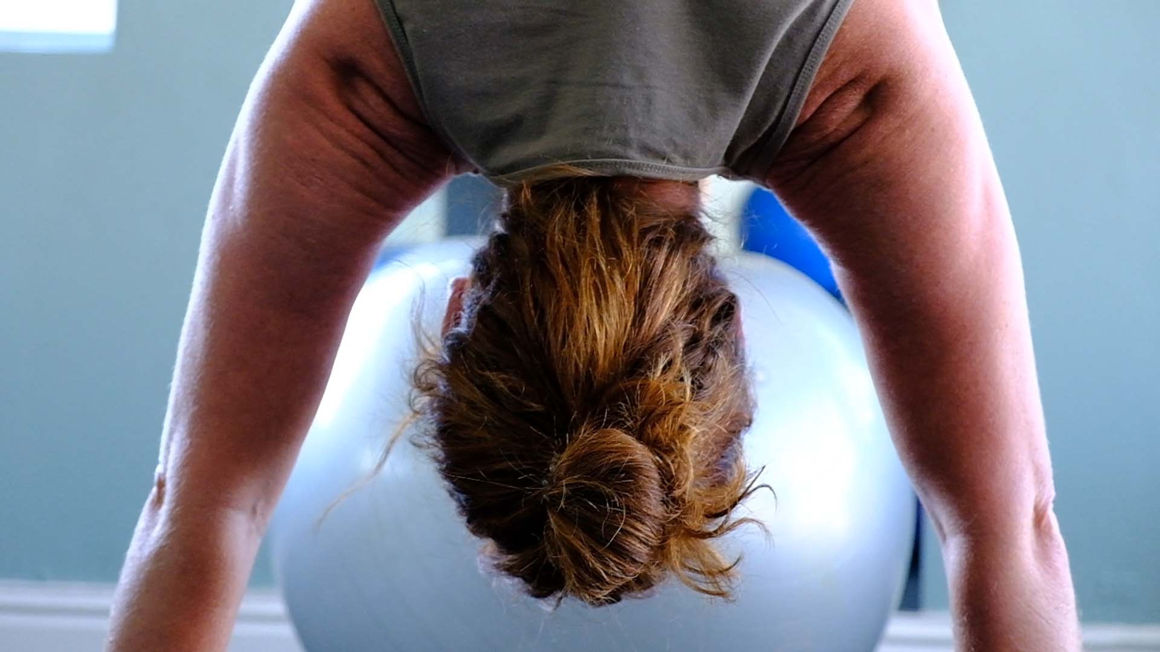 Upside-down view of a woman over a large grey stability ball