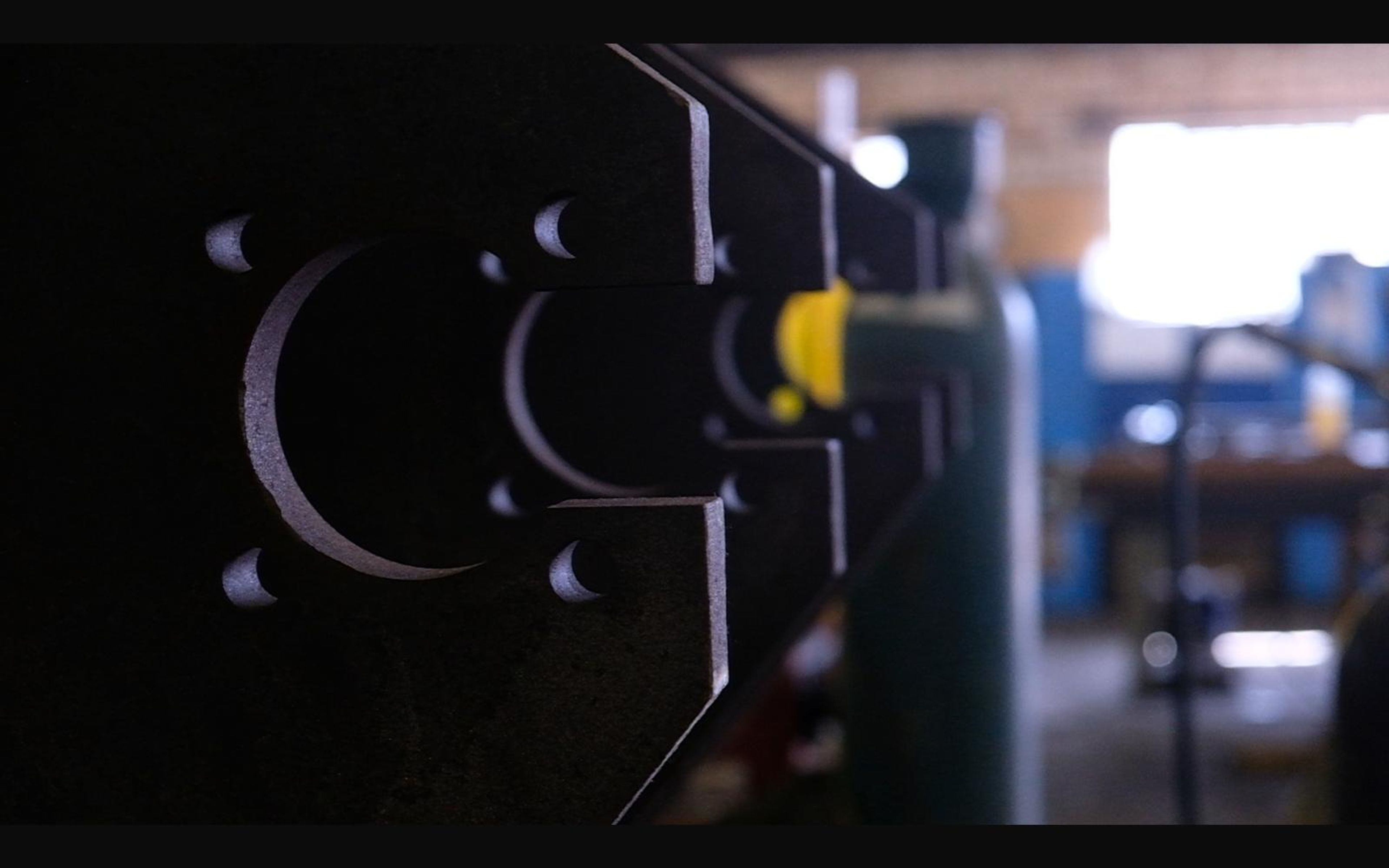 Steel plate with cut-out shapes and gas cylinders behind