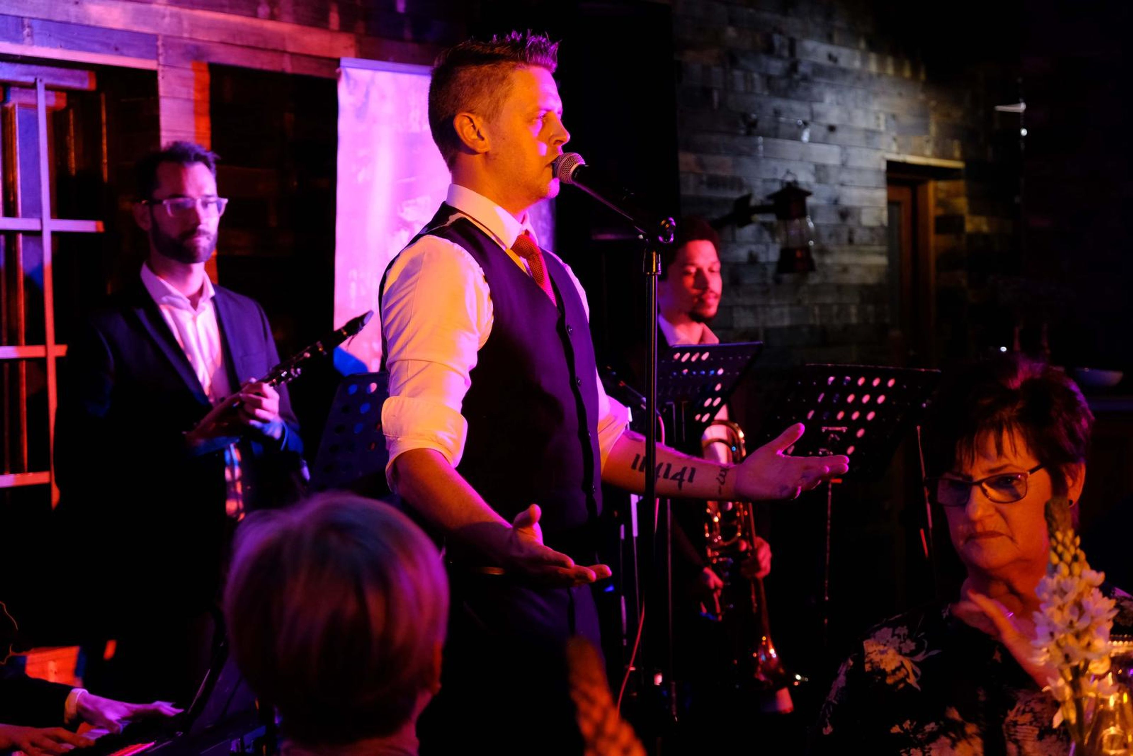 Singer in a waistcoat with the band behind him