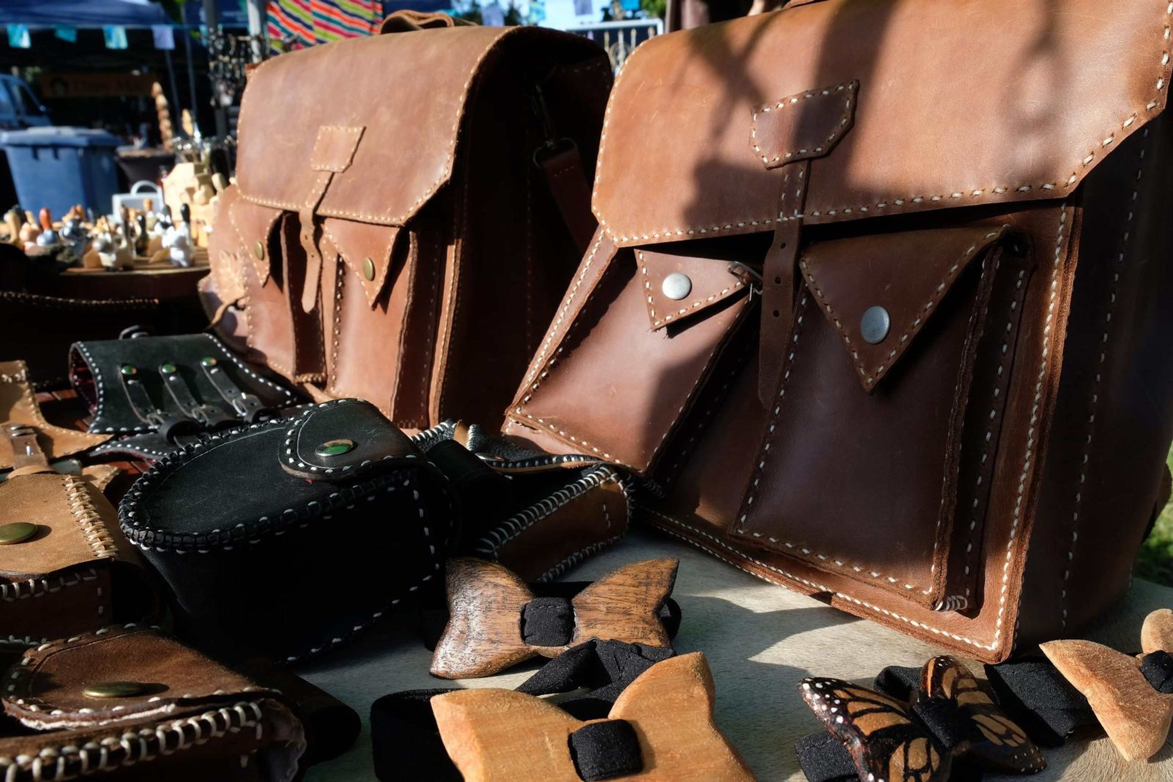 Tan leather satchel, black pouch and wooden bow ties at the Juuks stall