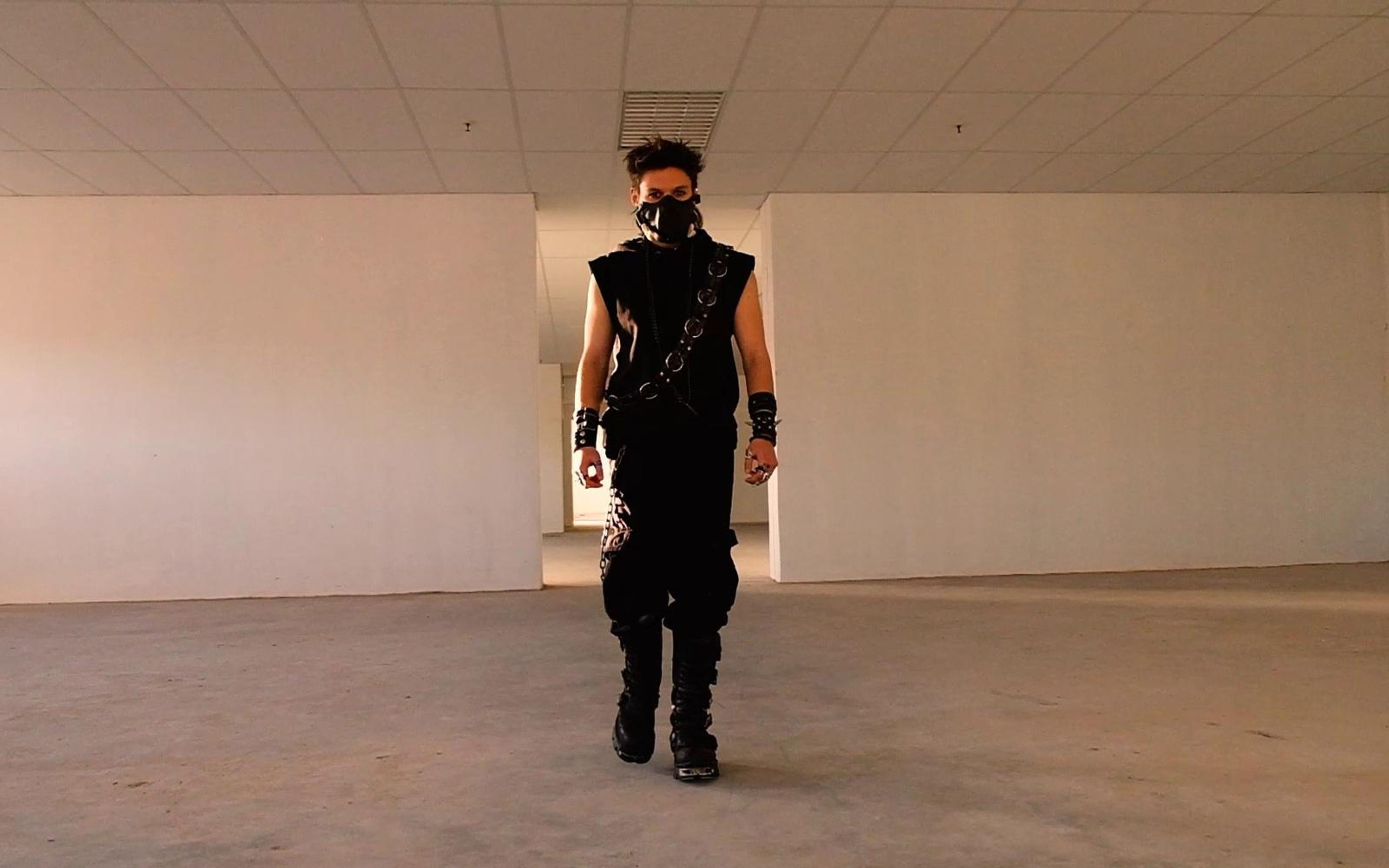 Warrior walking straight toward the camera across a wide empty room with white partition walls