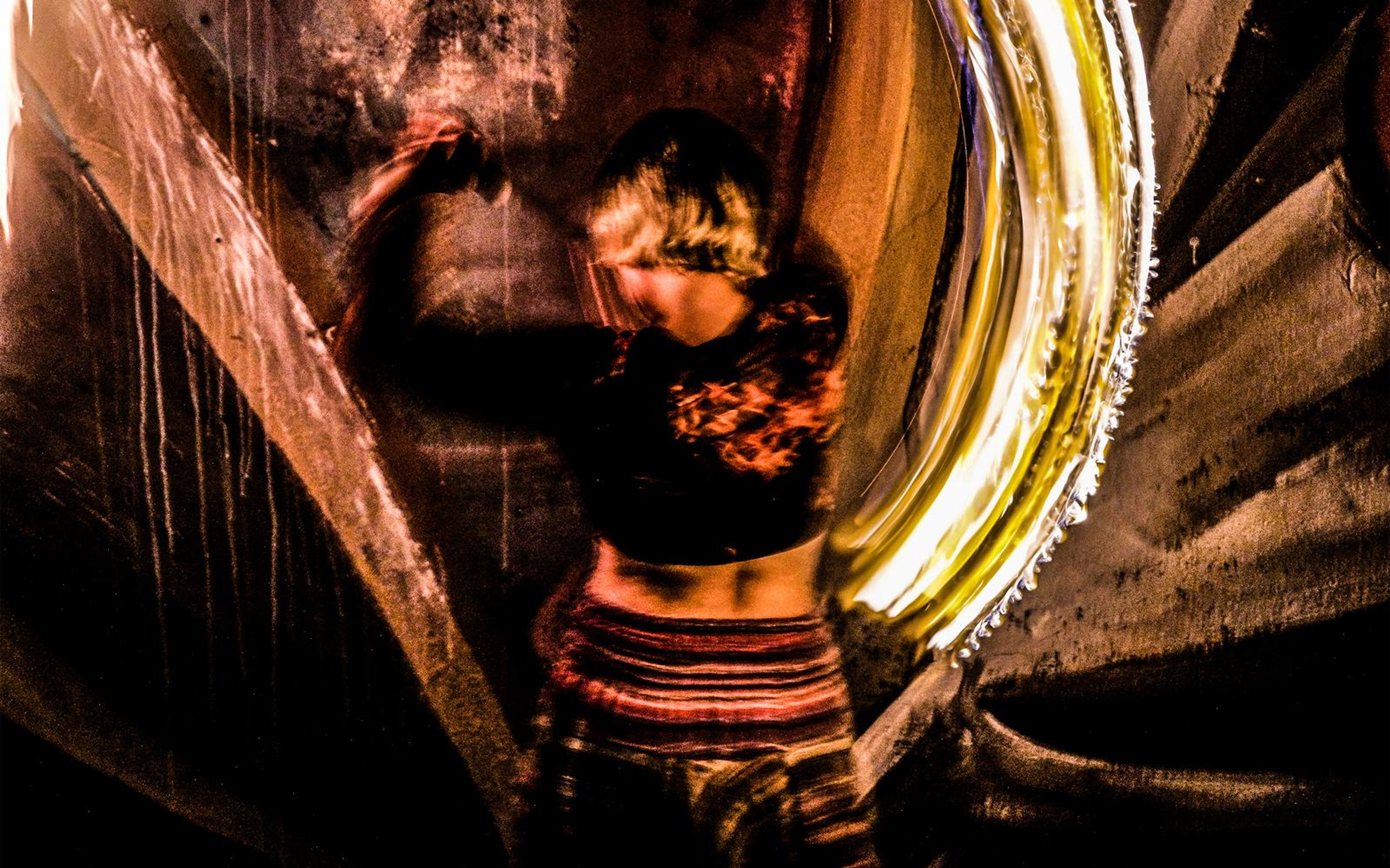 Performer in a red top with a golden arc of fire light swept to the right, hands blurred by motion