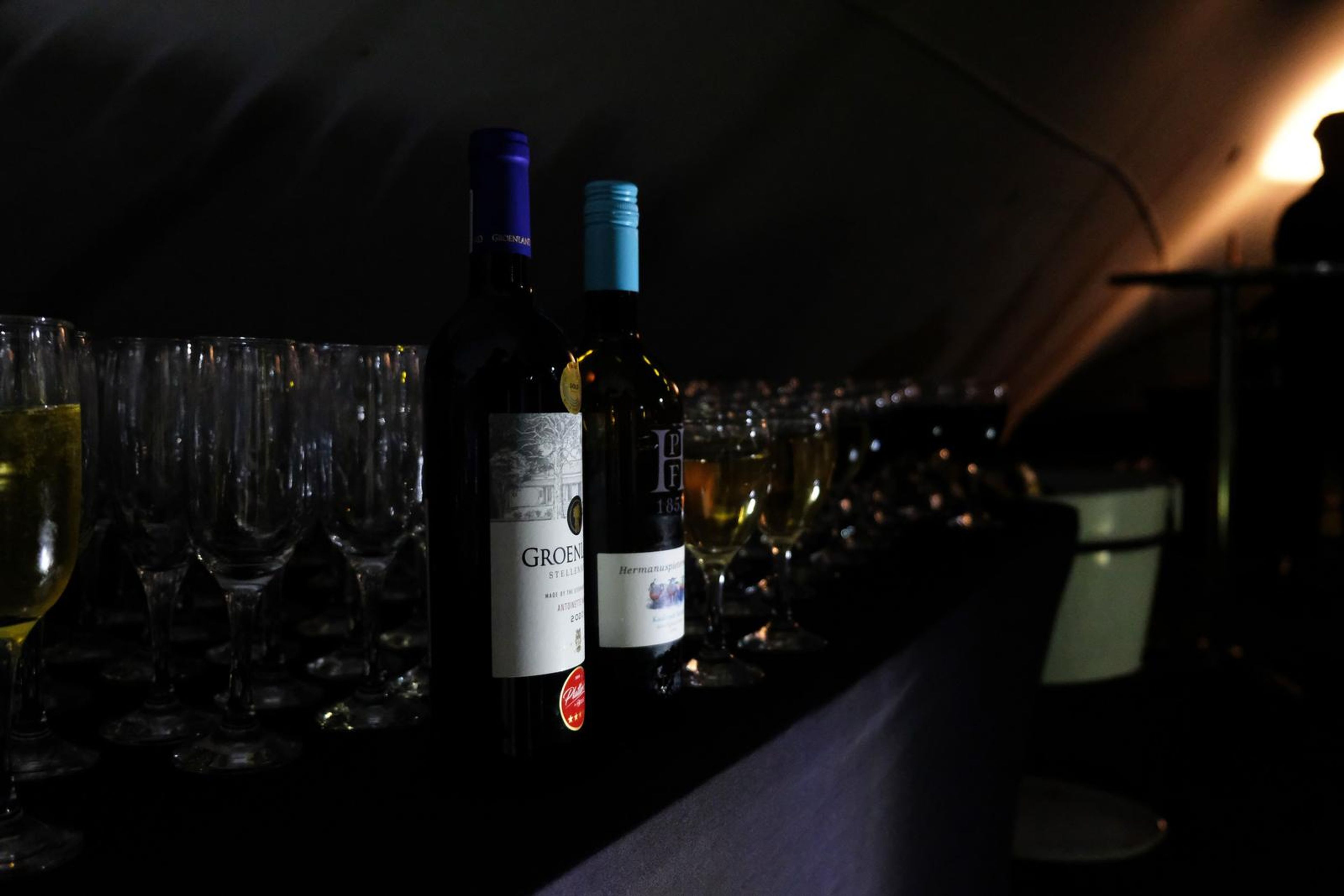 Wine bottles and champagne glasses on the bar in low evening light