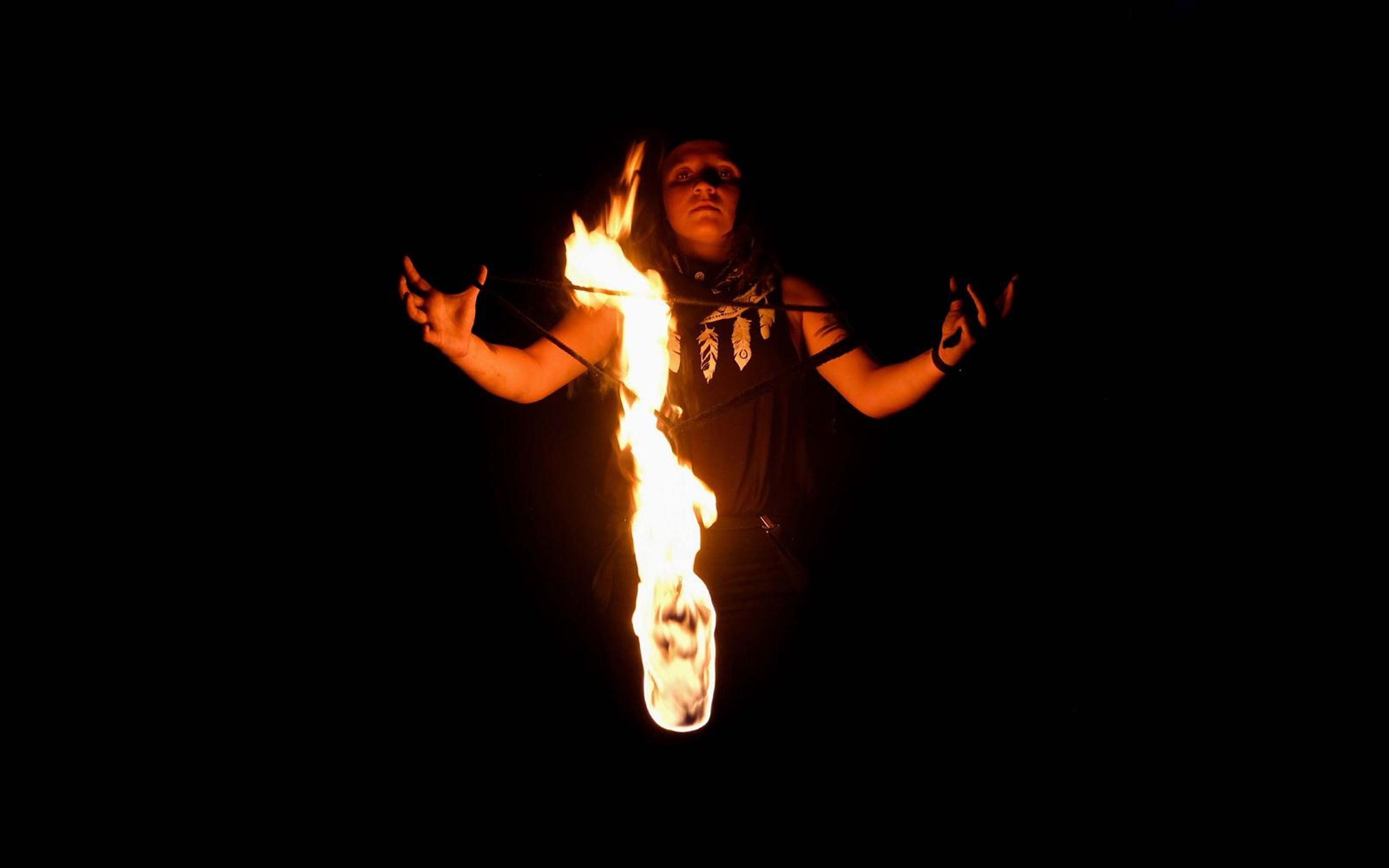 Performer with arms out to the sides and a tall narrow flame hanging in front of the body