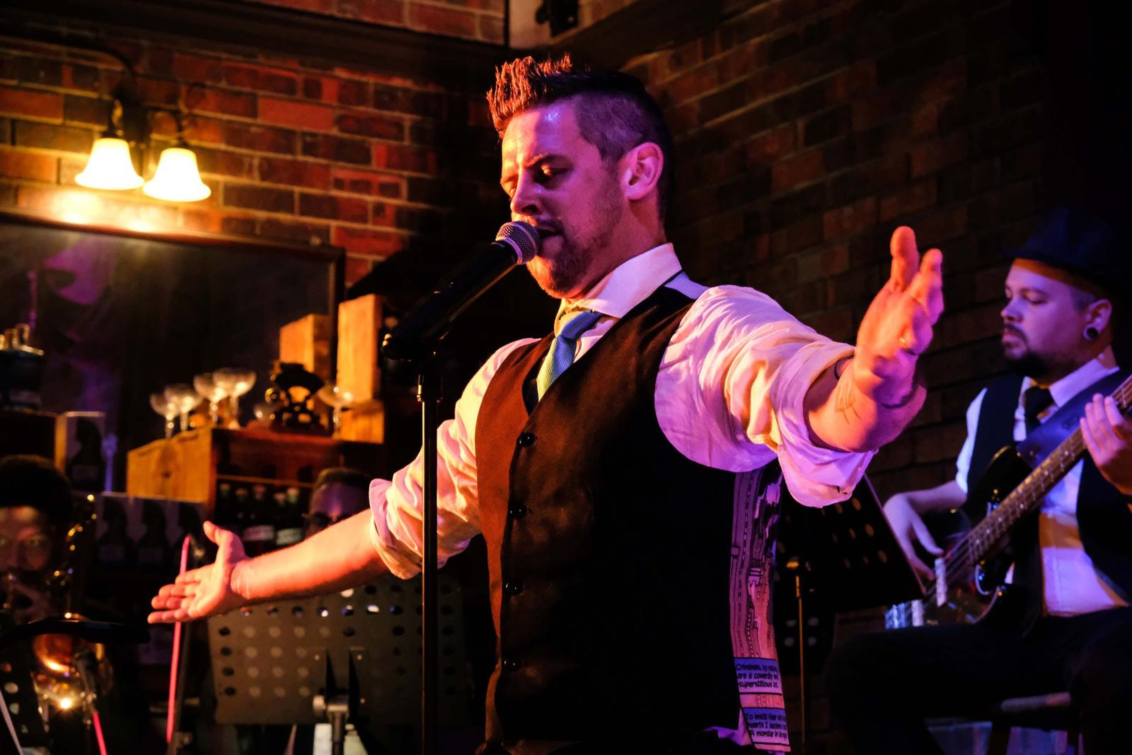 Lead singer with his arms outstretched beside the bassist in a hat