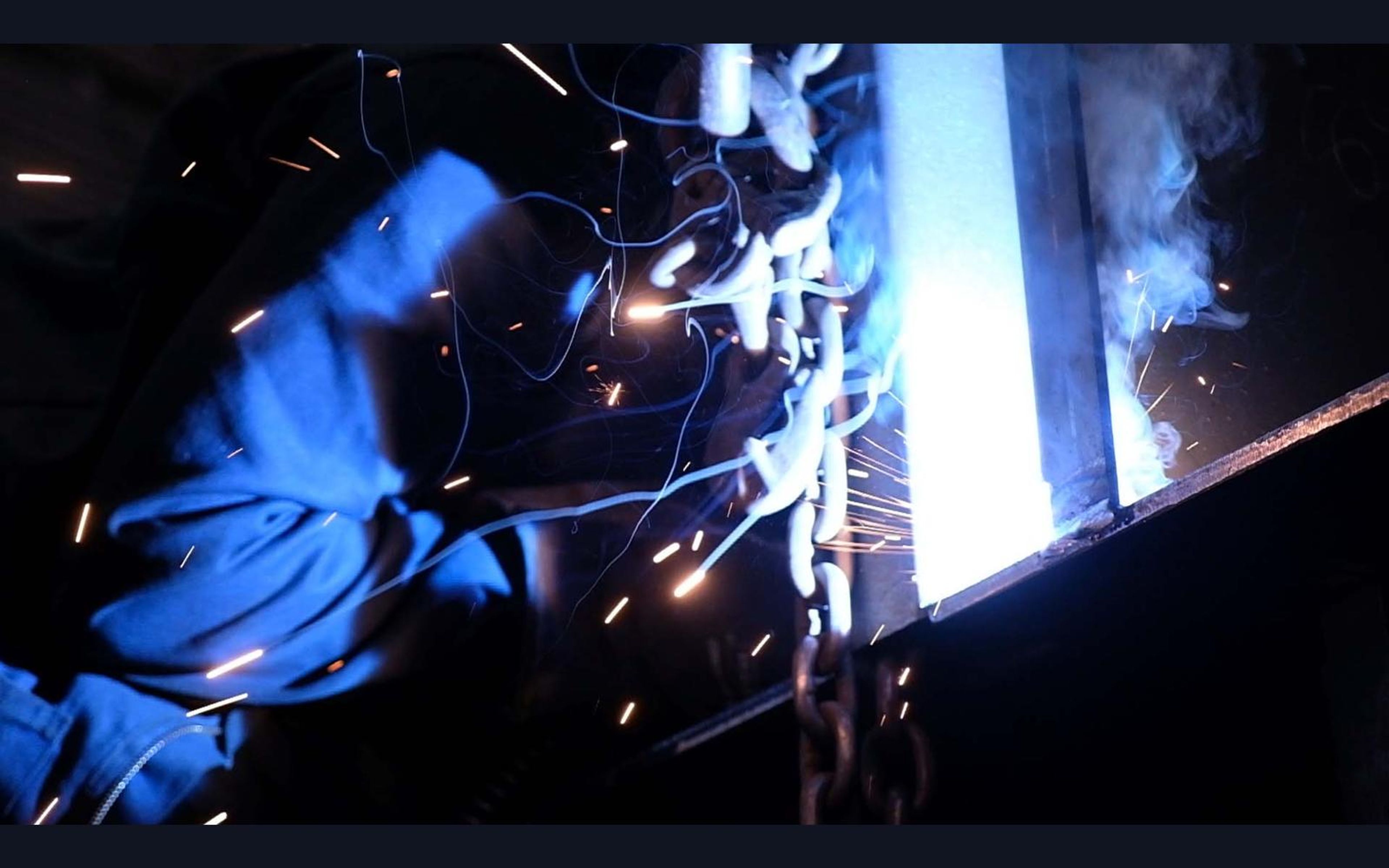 Distant welder lit only by the weld arc