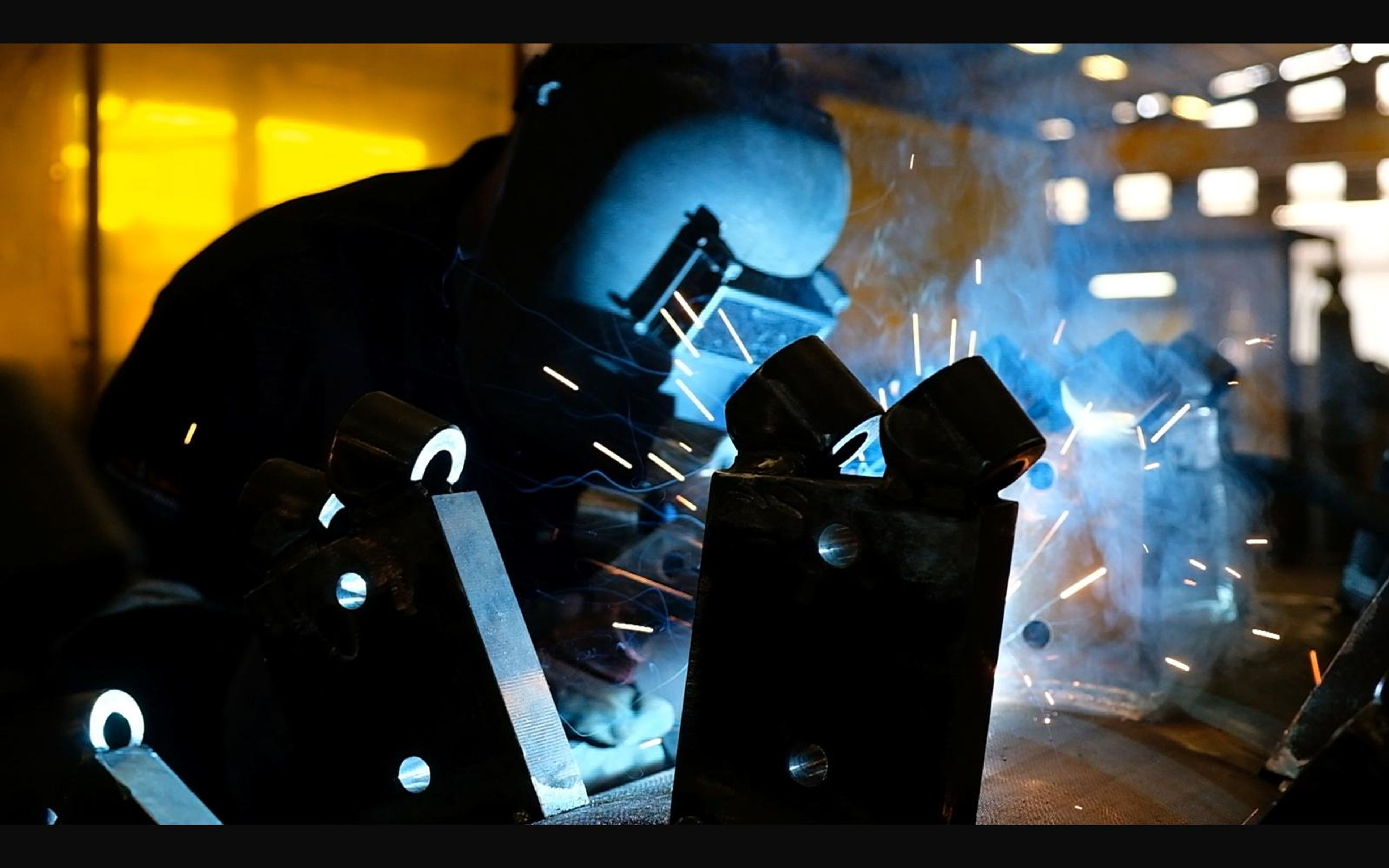 Welder working on brackets in a glow