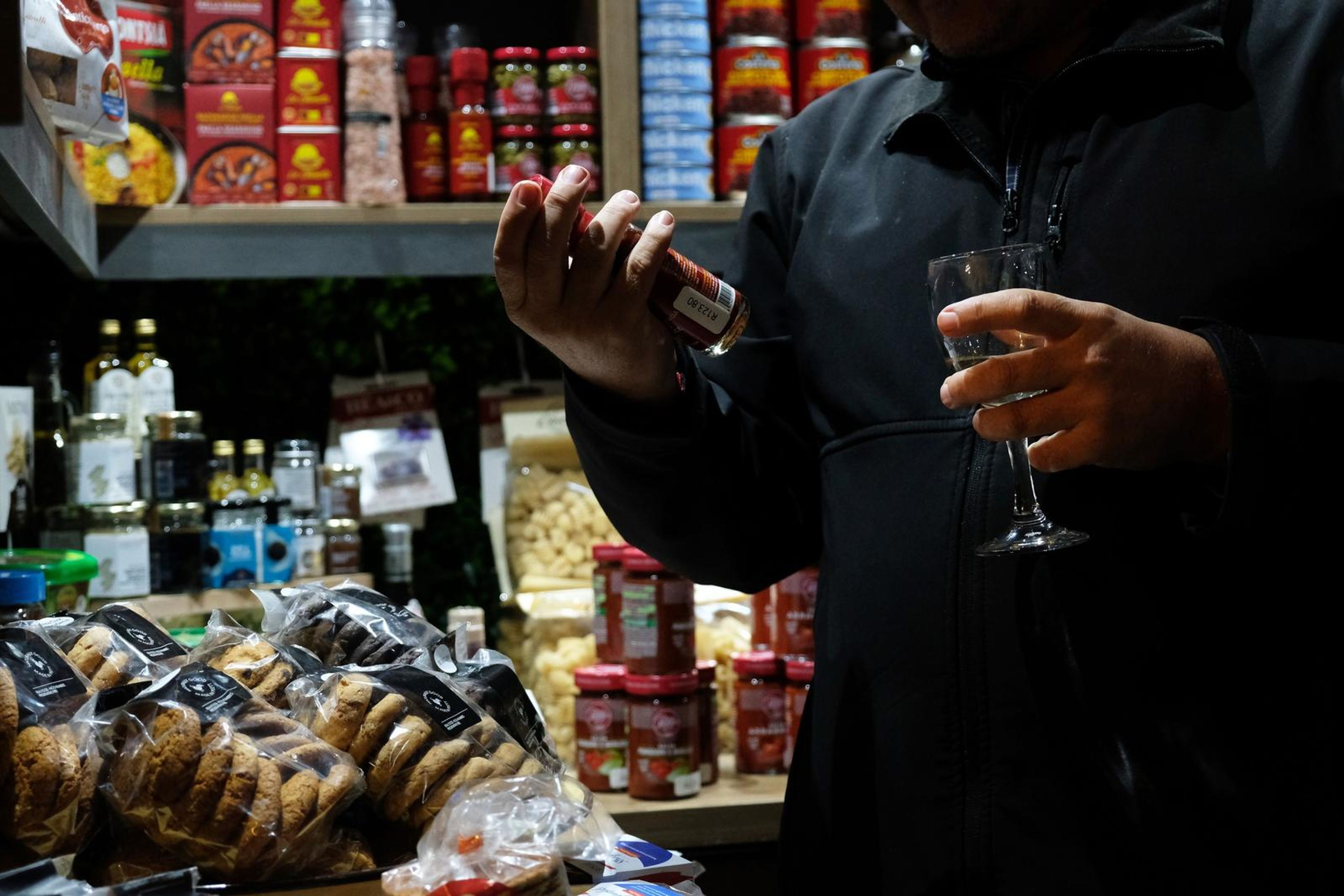 Guest holding a glass of wine in front of shelves of bread and biscuits