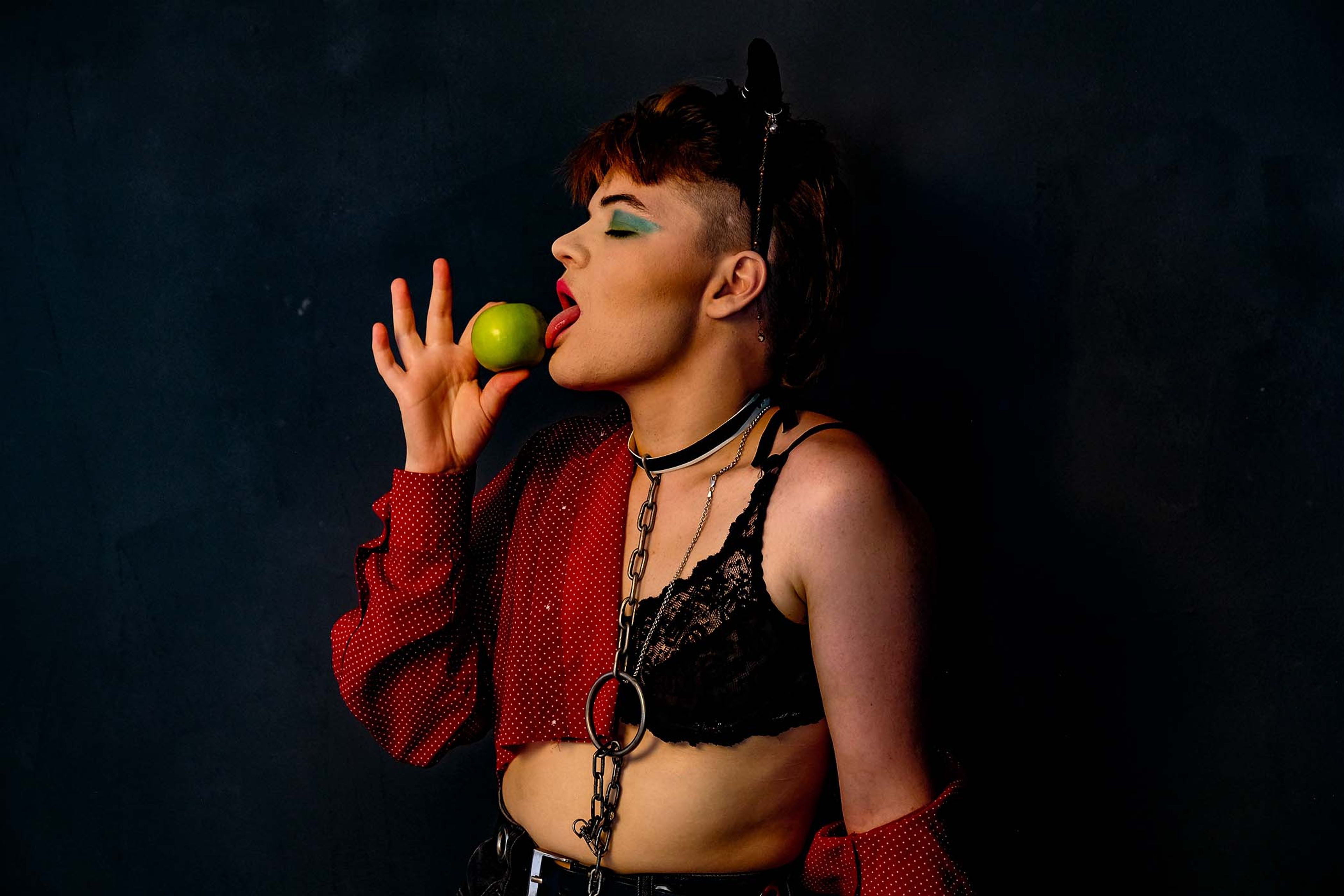 Portrait, subject in a lace bra and chain choker holding a lime up to the mouth