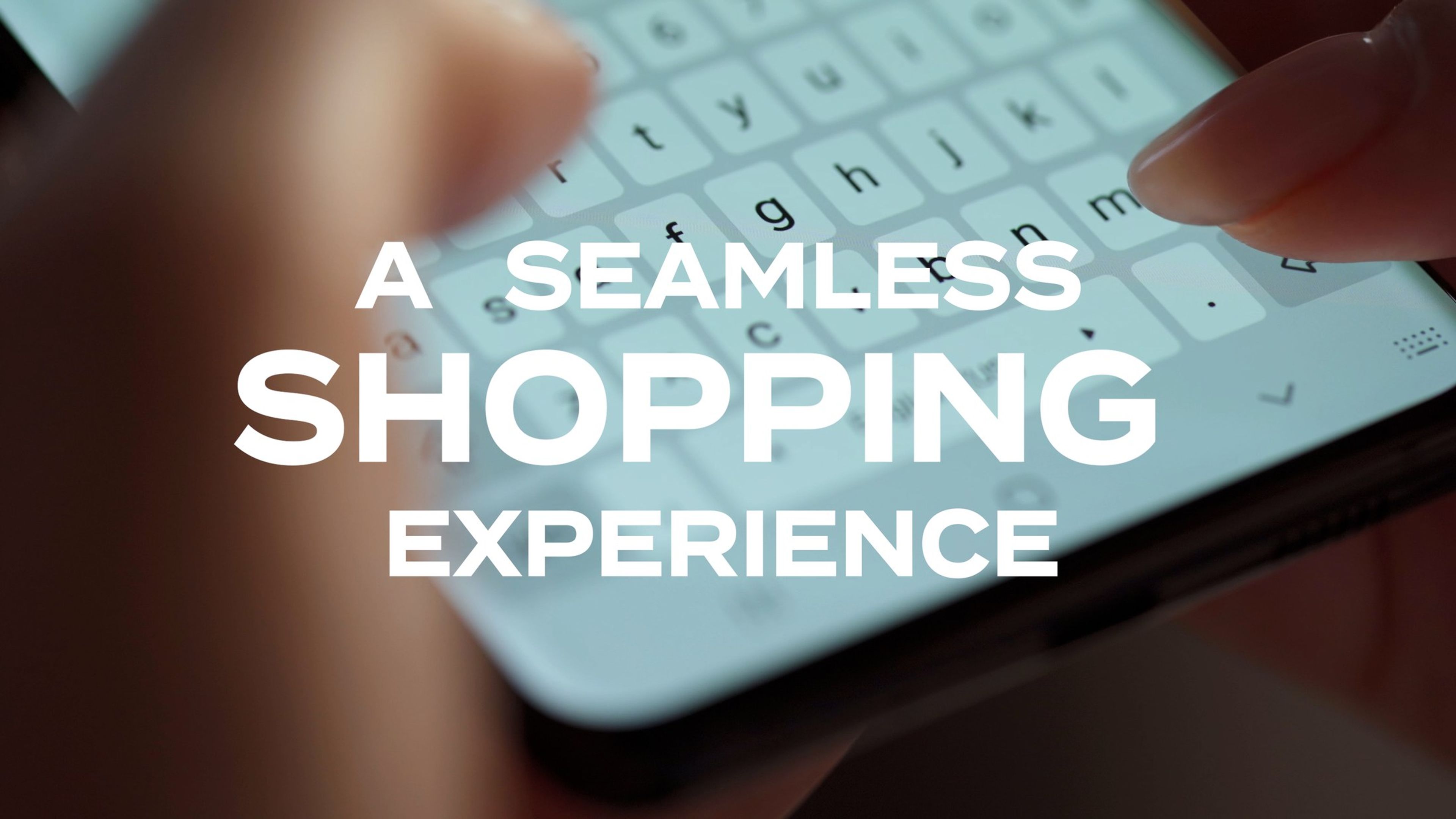 Fingers typing on a phone keyboard under the text 'A seamless shopping experience'