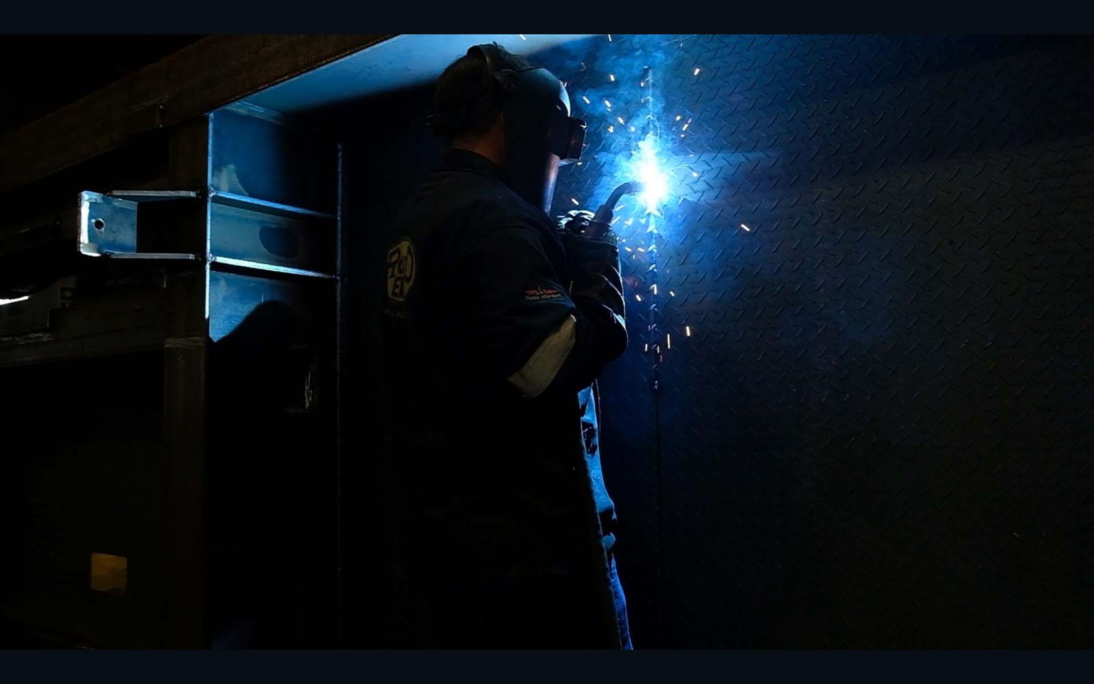 Welder in the dark with a bright arc and sparks