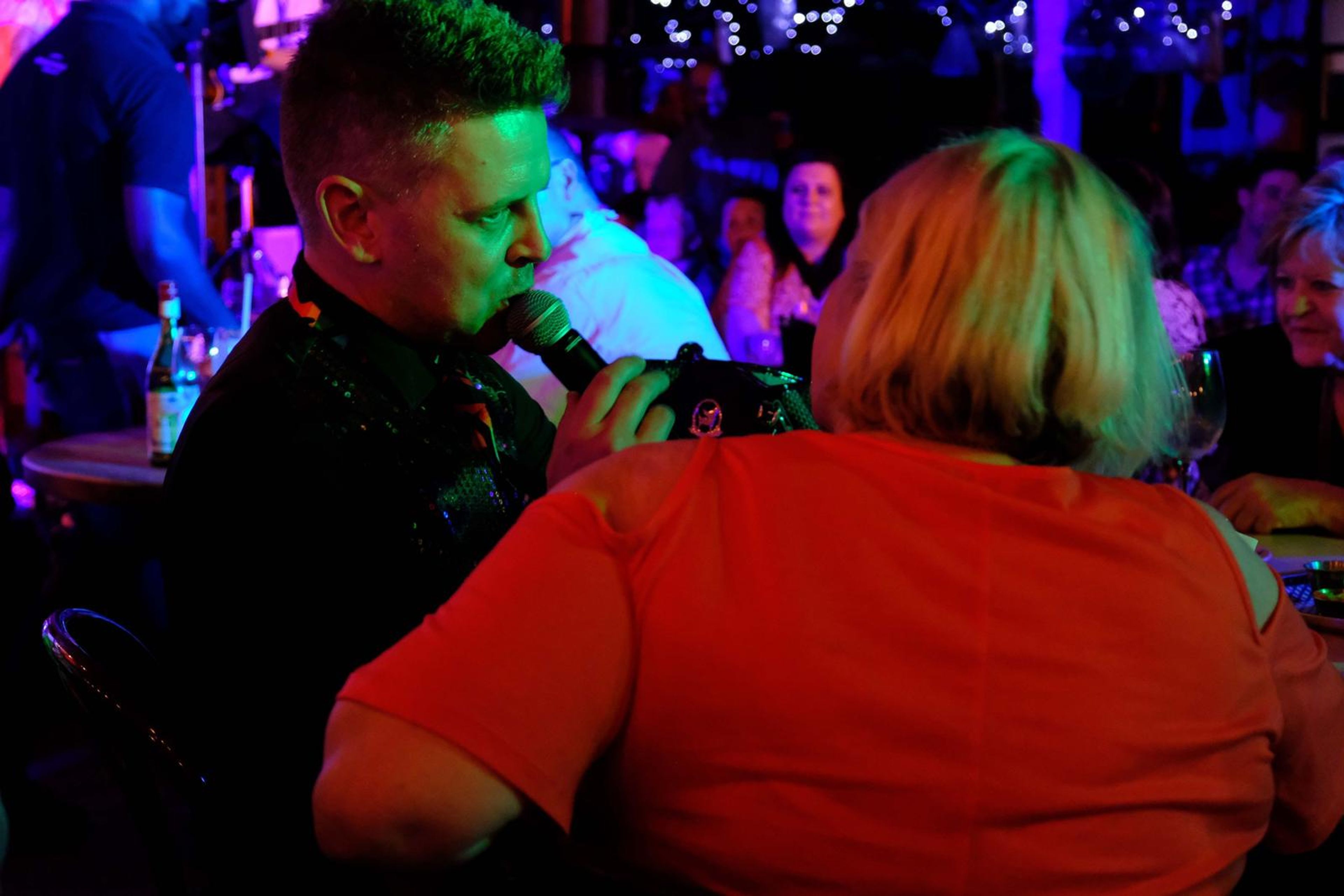 Singer singing into the microphone beside a seated guest