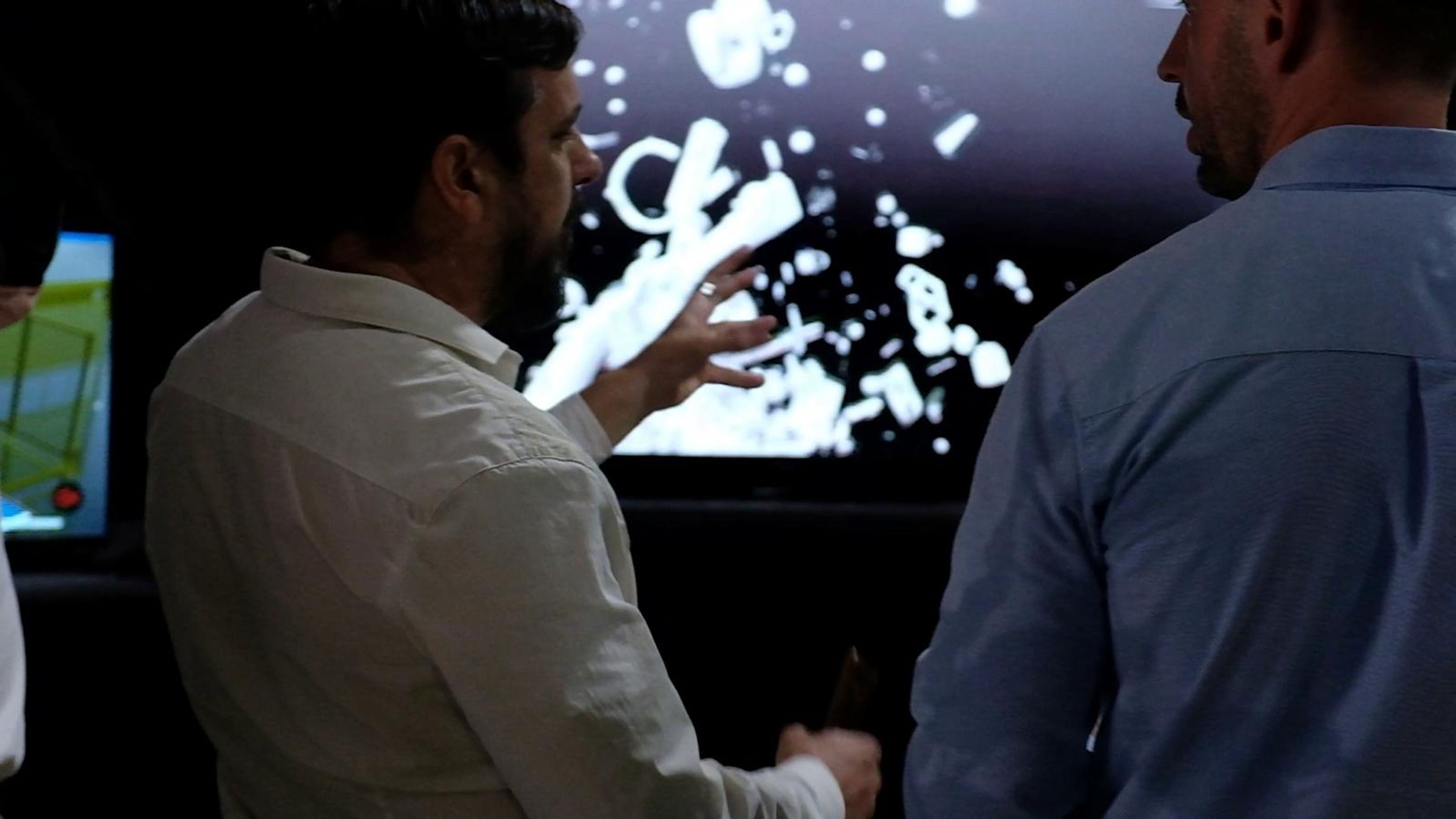 Two exhibitors discussing a digital screen