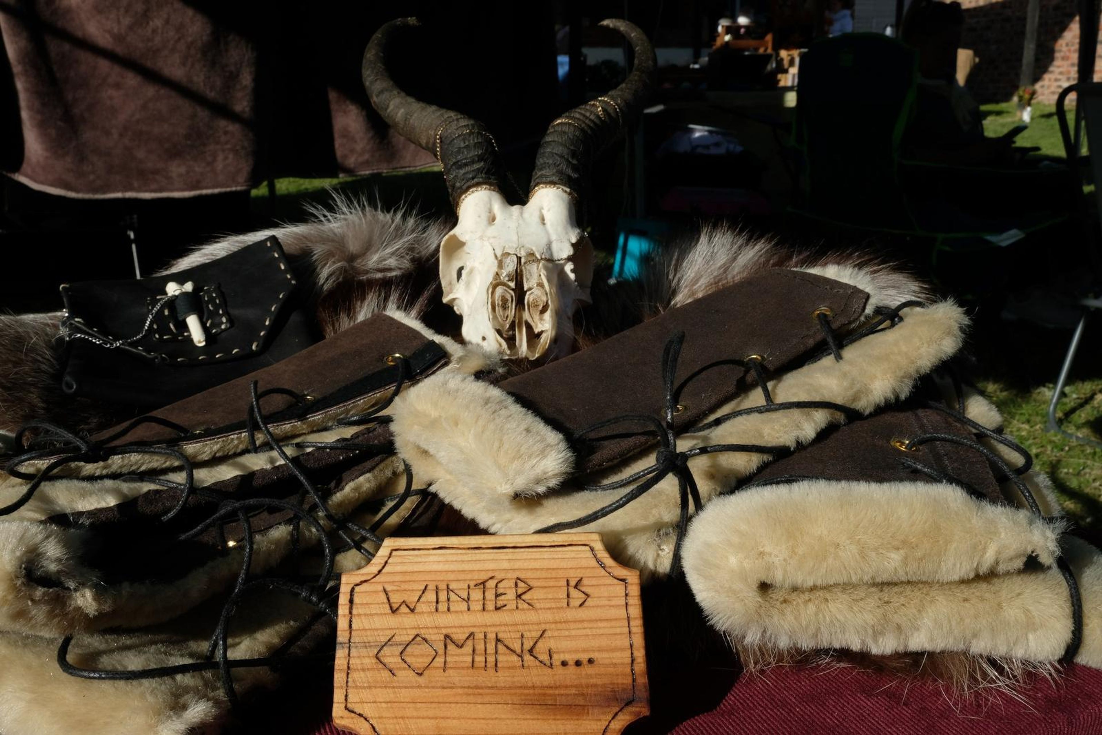 Fur-lined leather arm wraps with lacing next to a Winter Is Coming sign