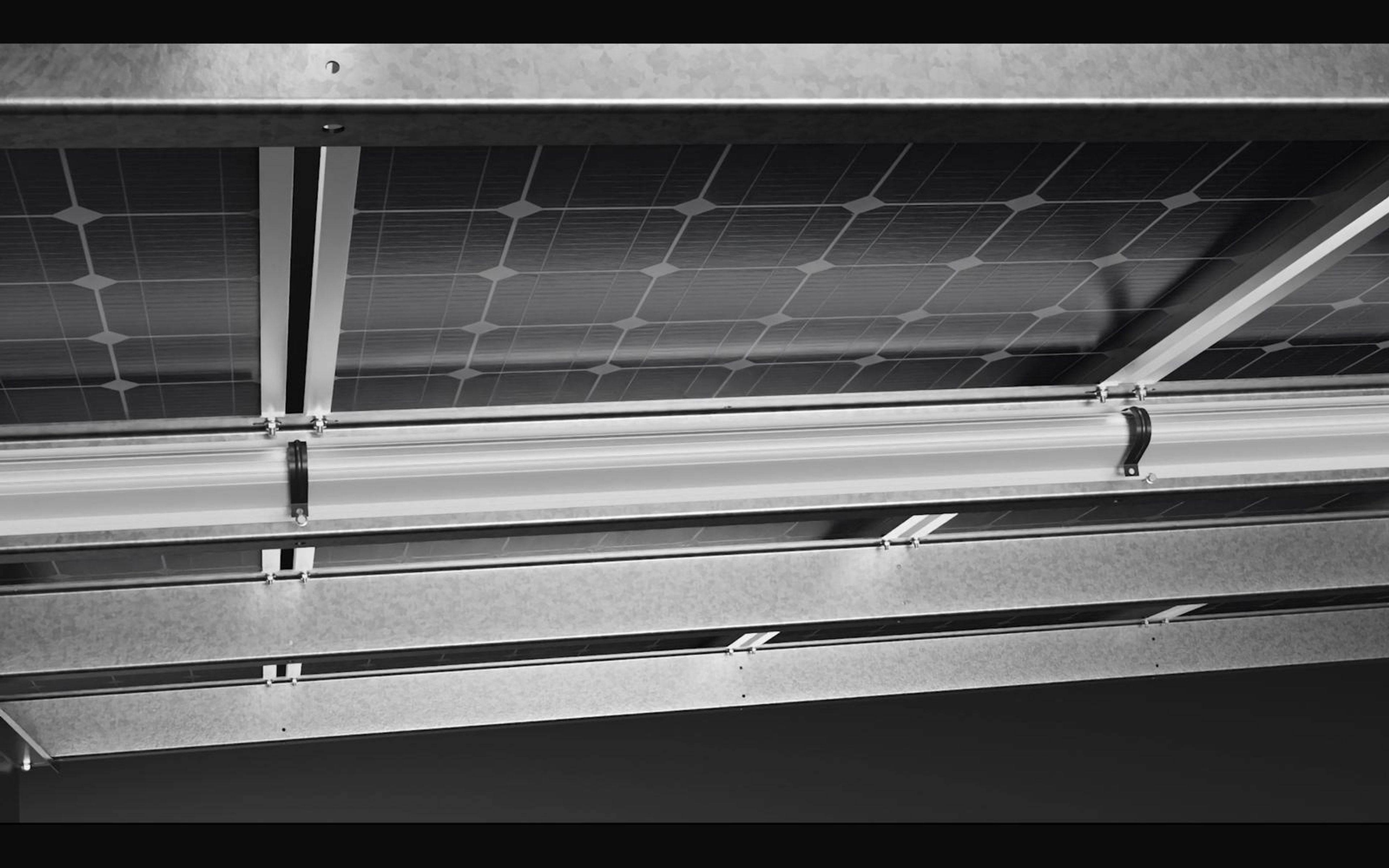 Underside view of solar panels clamped to galvanised rails