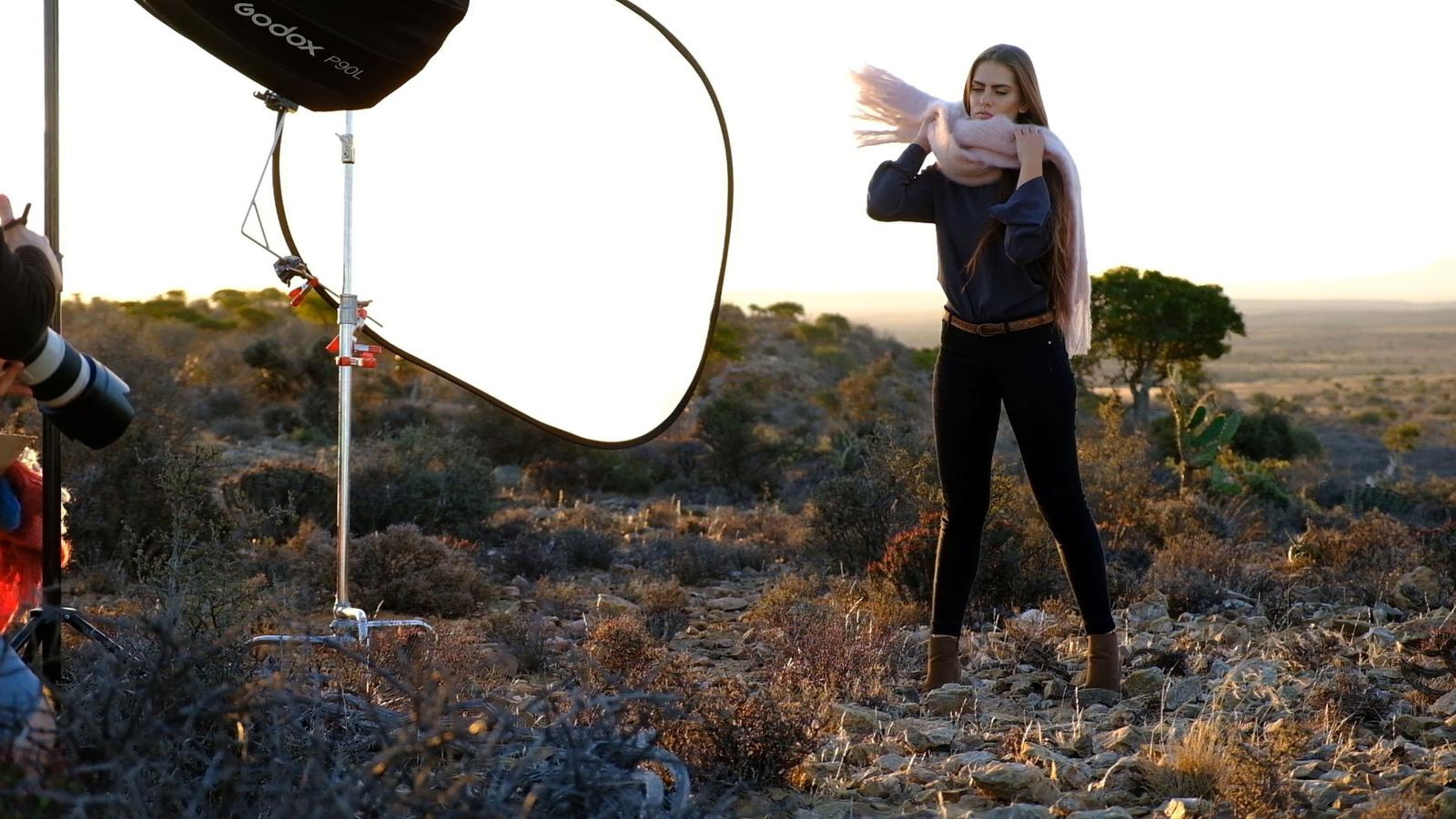 Model tossing a scarf in front of a softbox on the hill