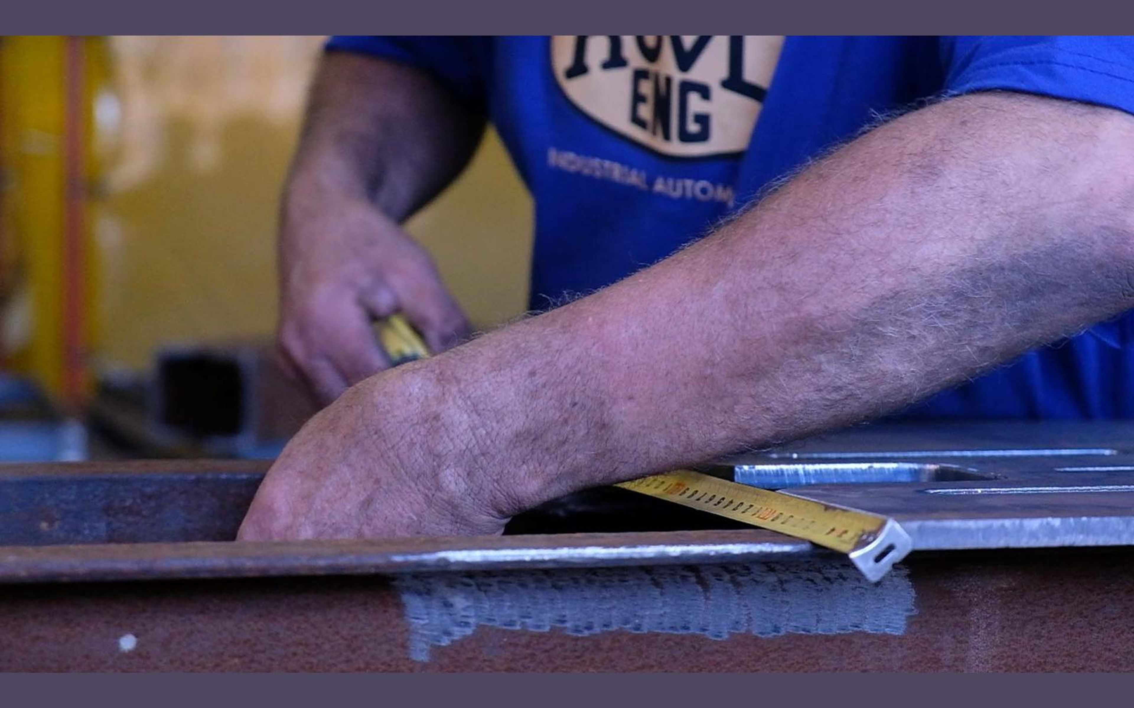 Fabricator in a ROVD shirt working at a steel bench