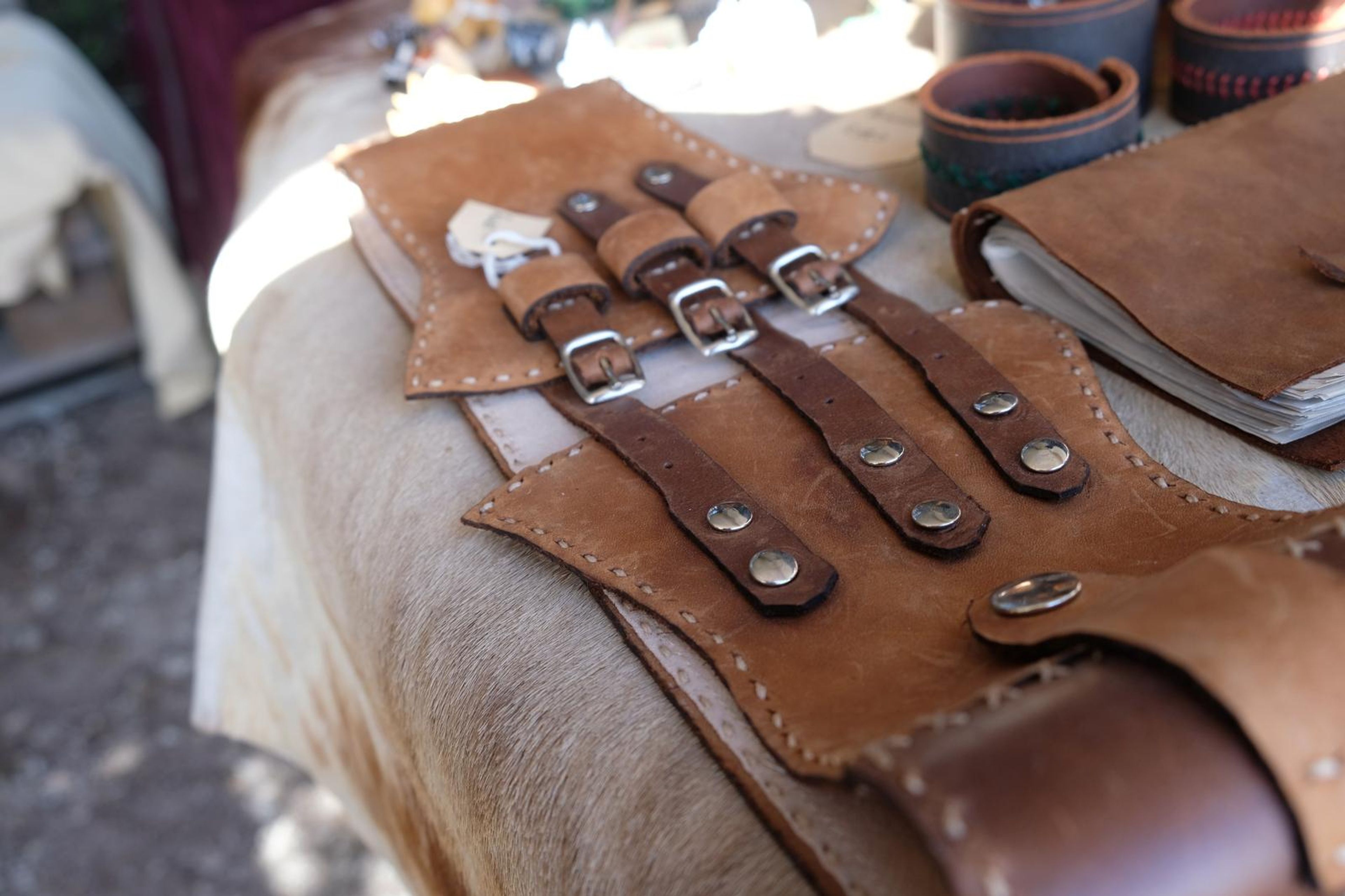 Tan leather buckled wrist guard on a hide-covered stool