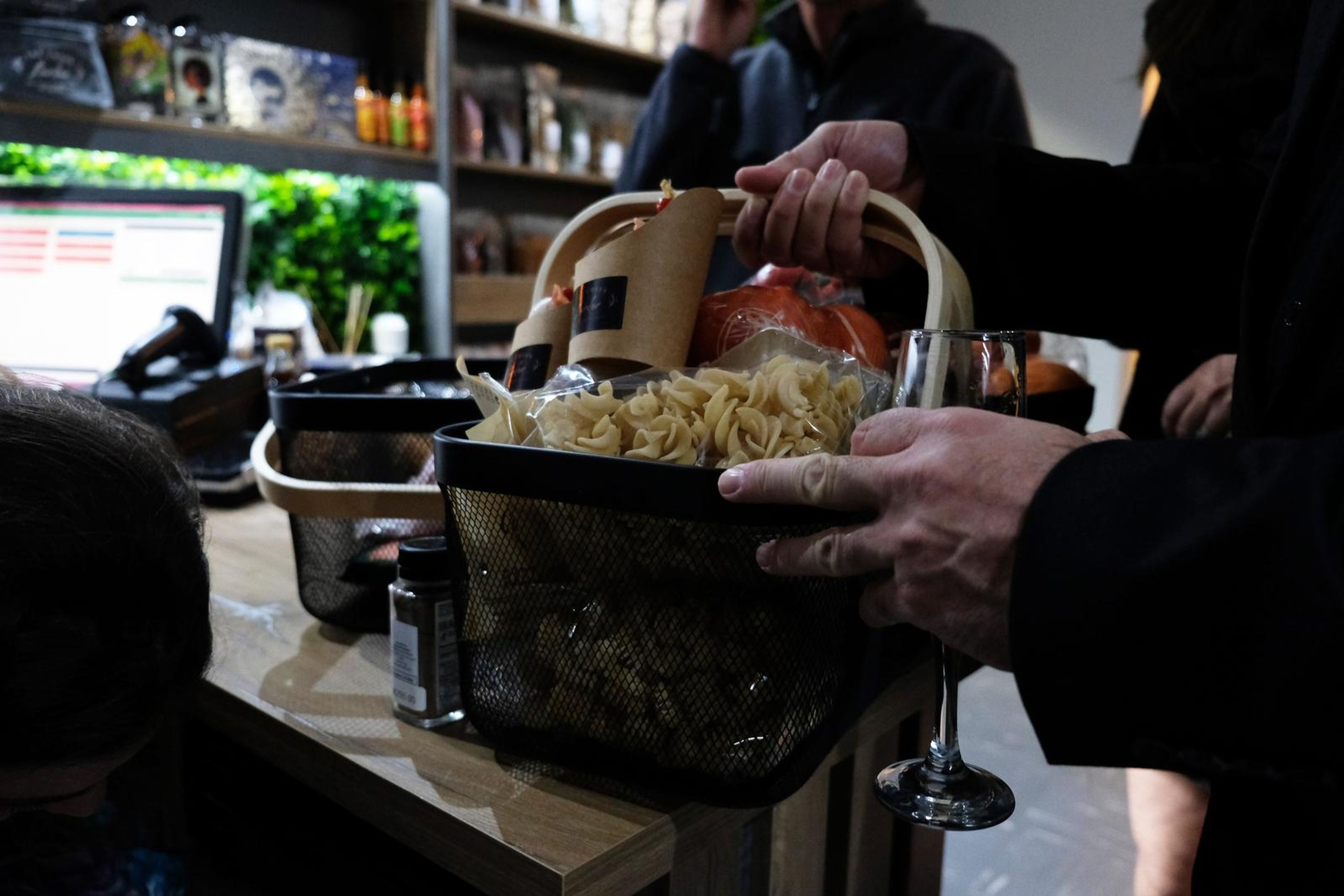 Hands carrying a basket of pasta at the till