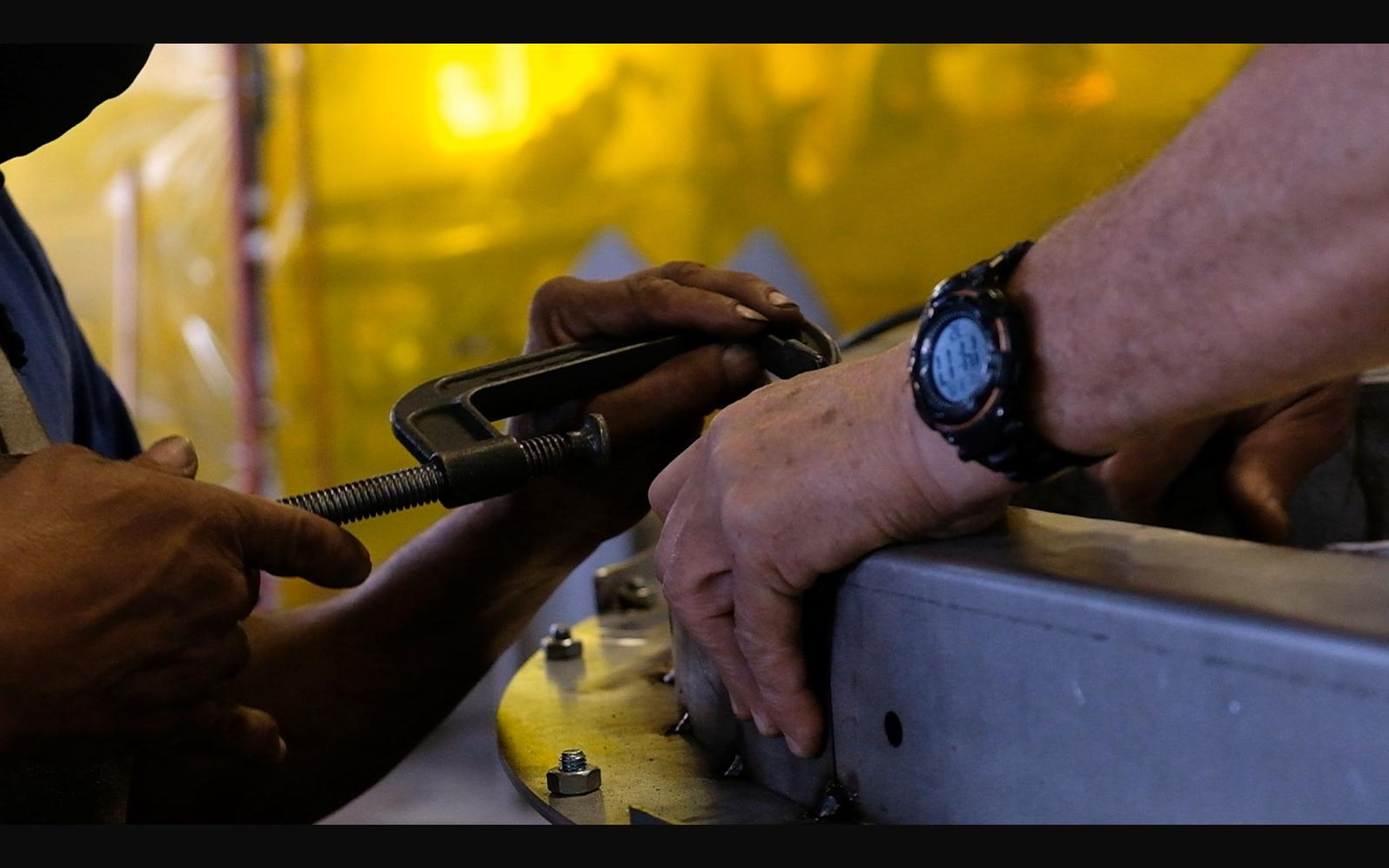 Hands holding a torch against a steel edge