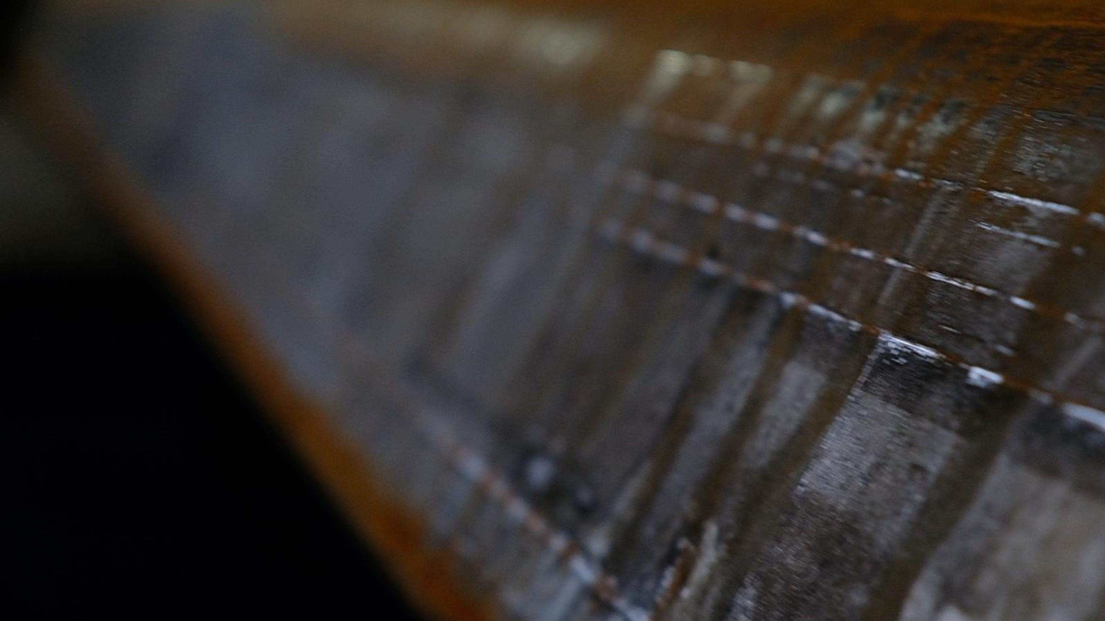 Close view of a steel plate surface with warm light along its edge