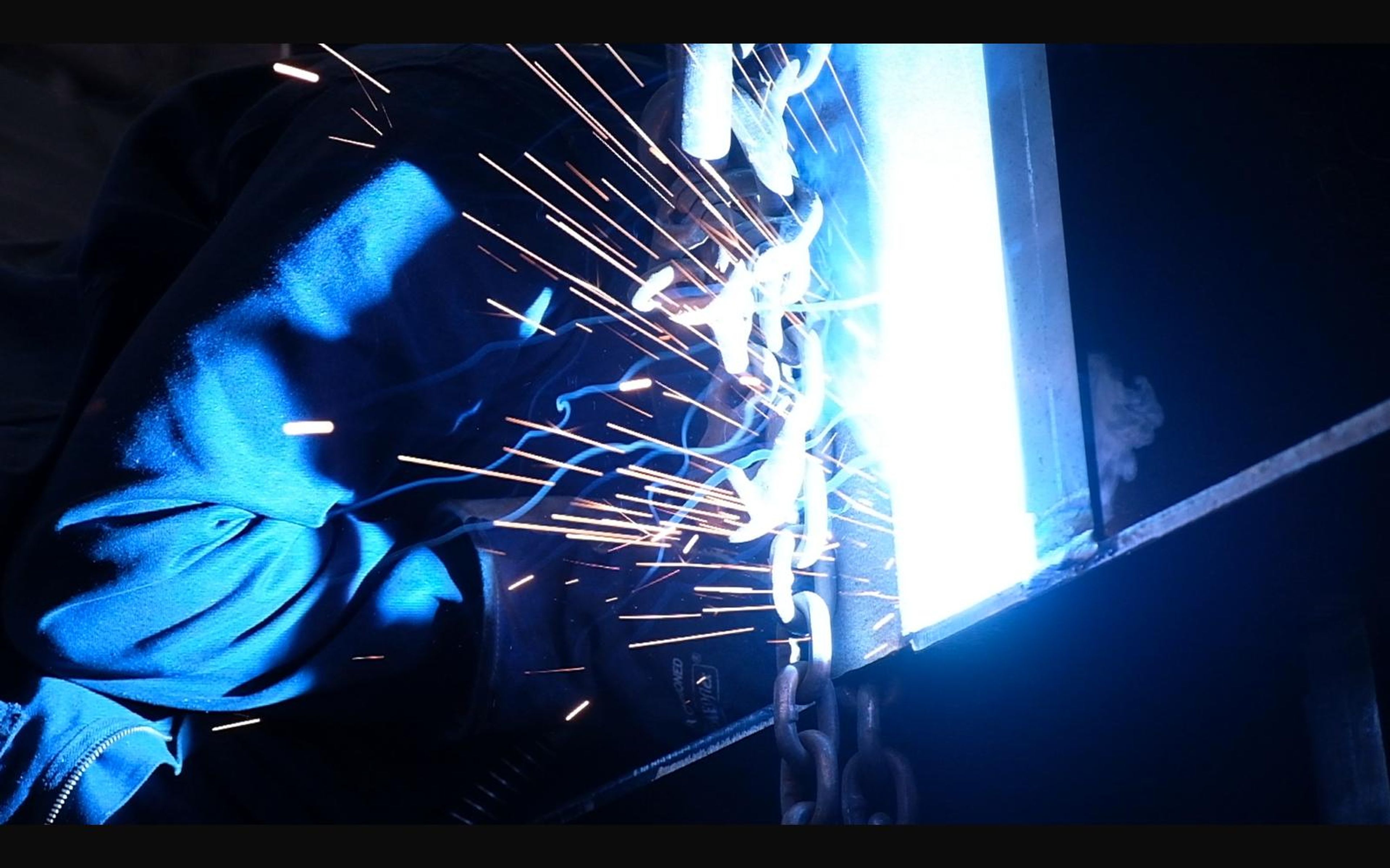 Welder with sparks flying in blue light