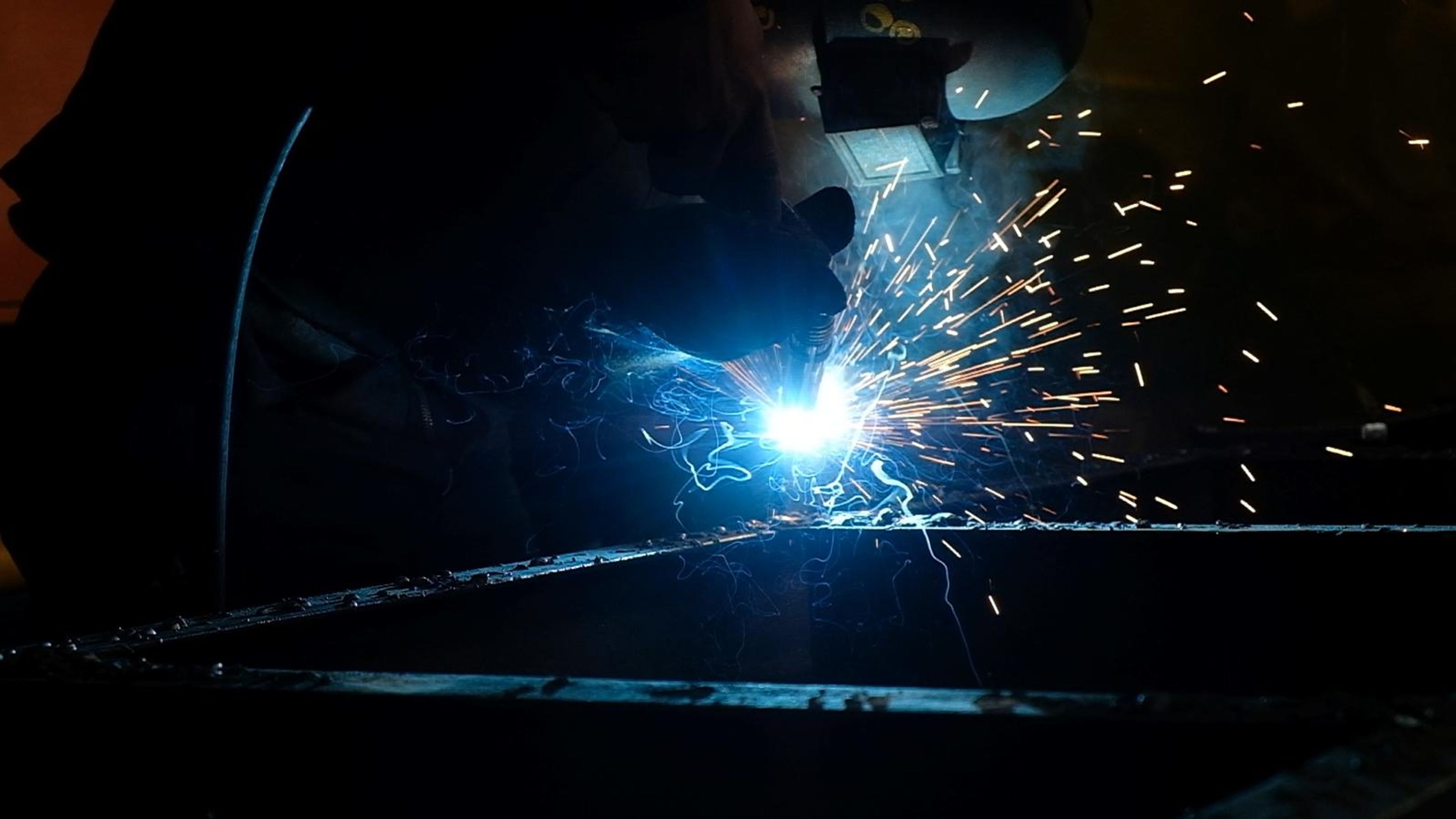 Bright welding arc and sparks along a steel edge