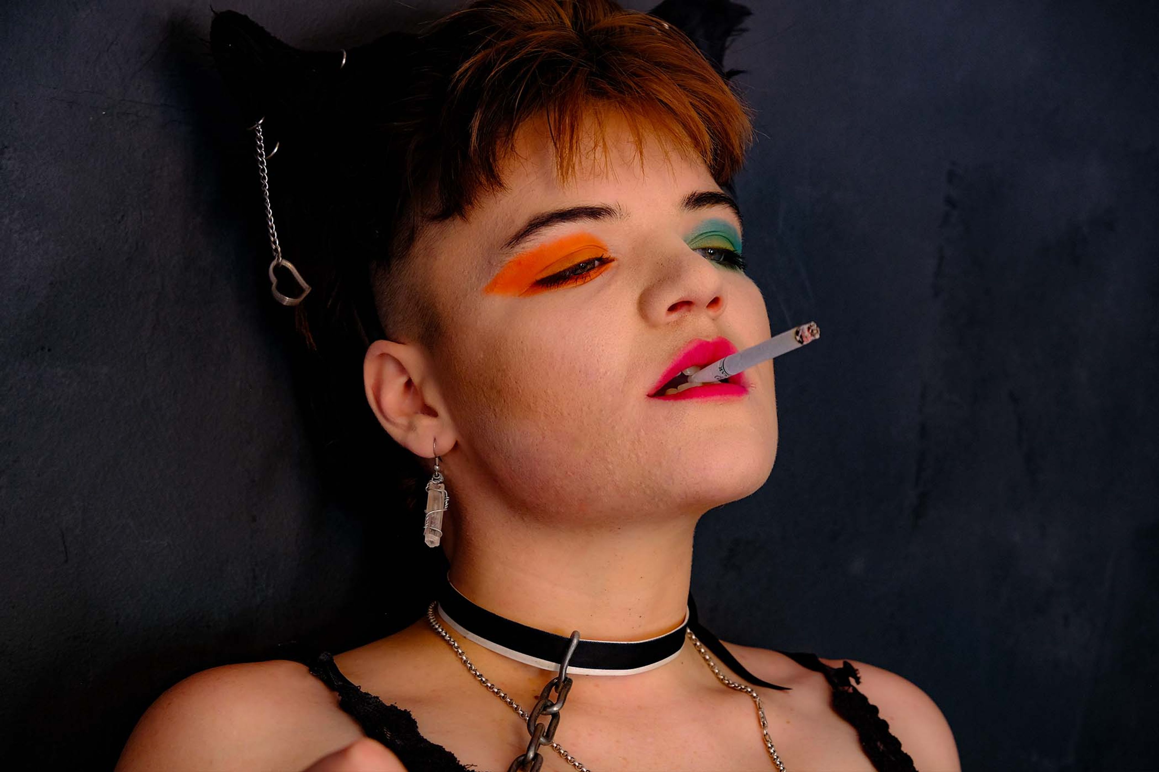 Close-up portrait, subject in a chain choker smoking a cigarette, head tilted back