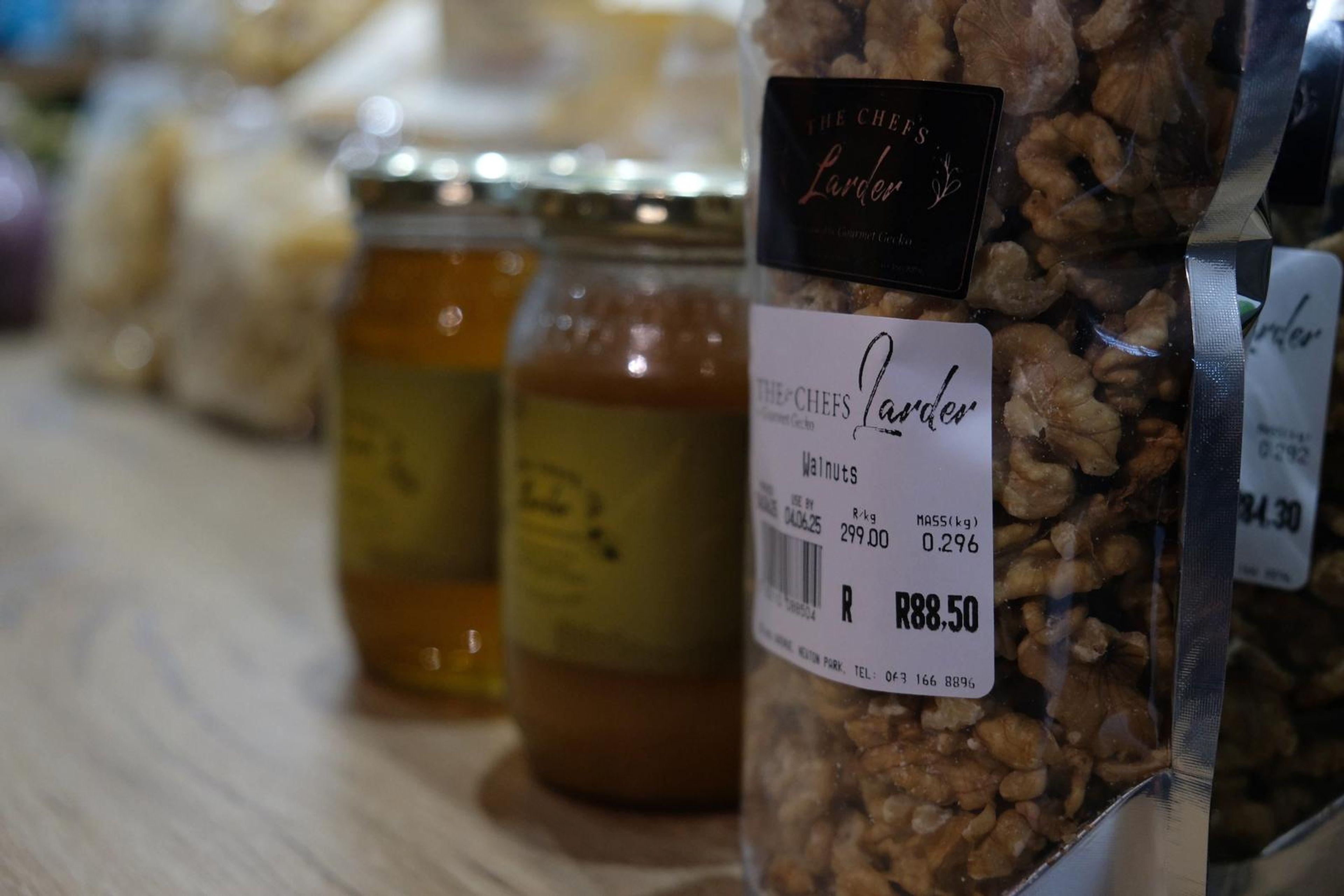 Honey jars and a bag of walnuts with Larder price labels on the counter