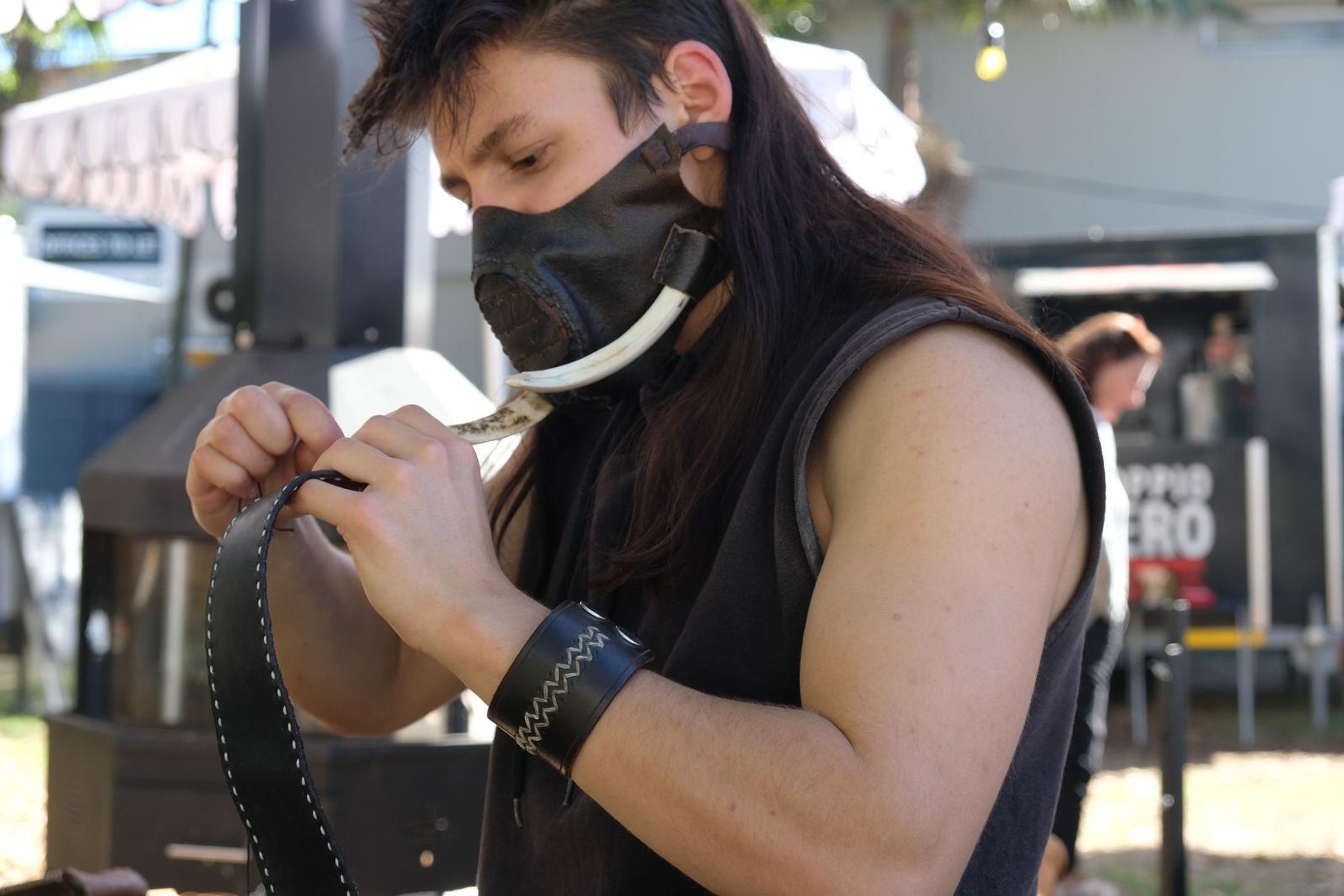 Close-up of the maker hand-stitching a leather strap