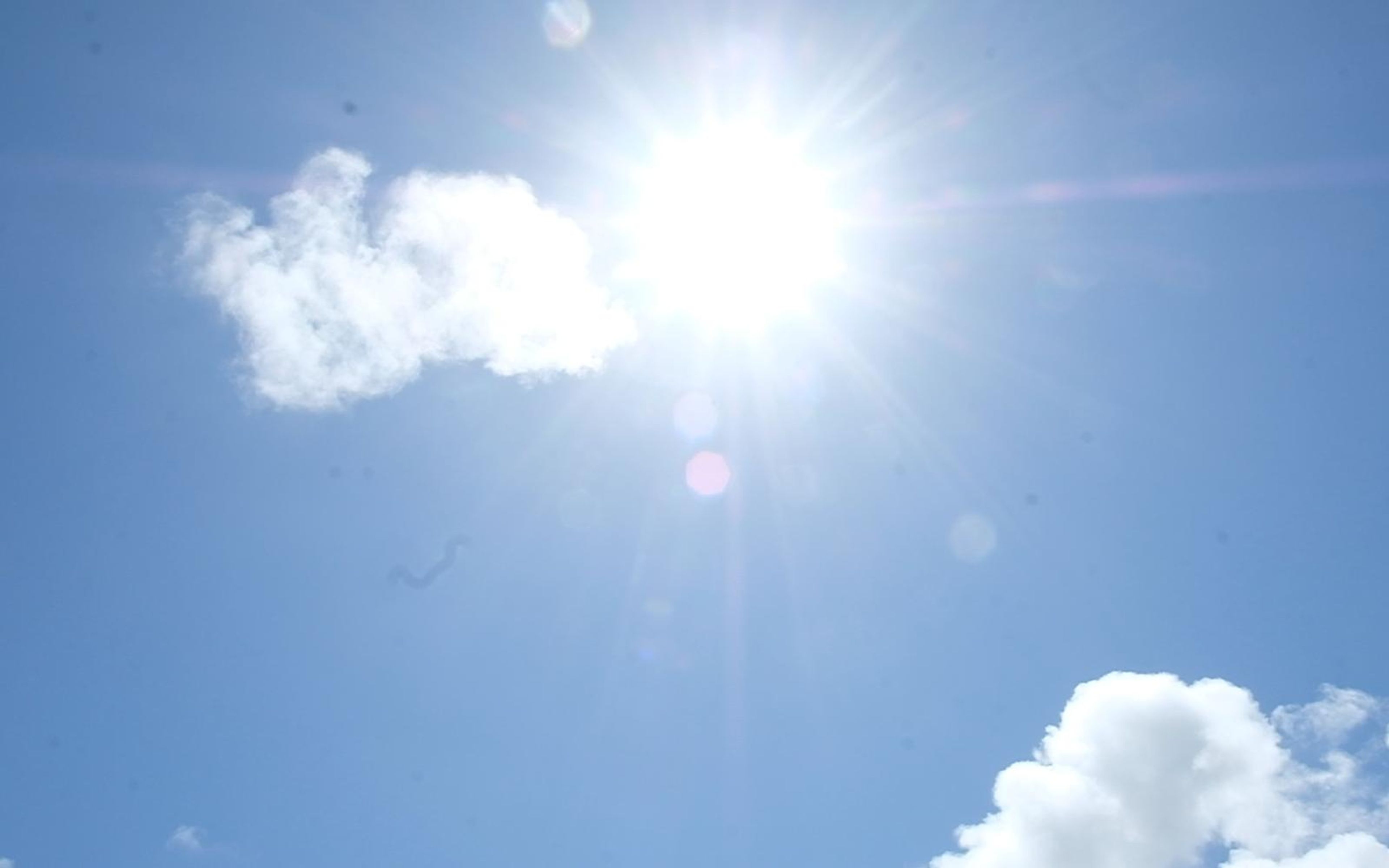 Bright sun and white clouds in a deep blue sky