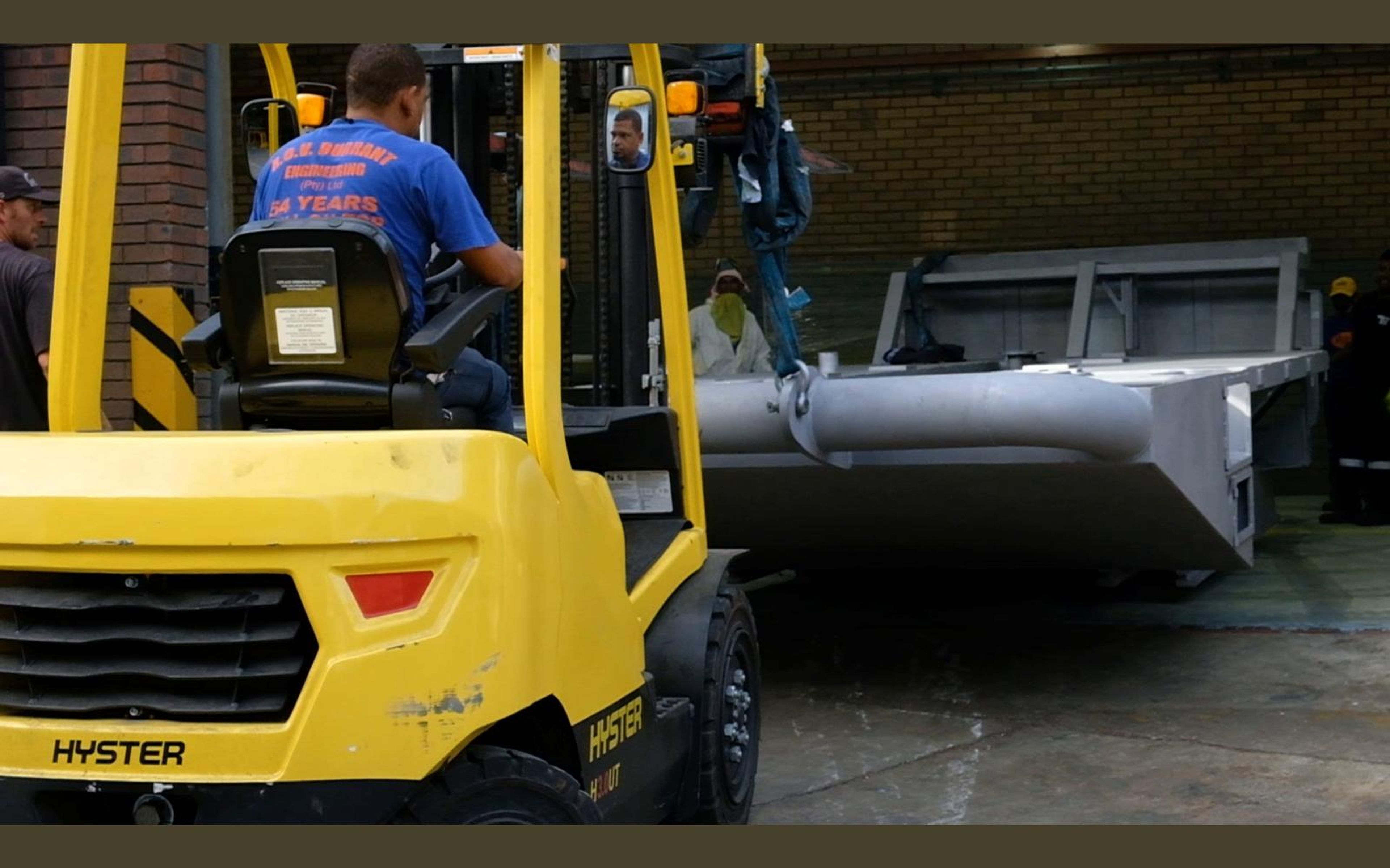 Forklift moving a grey steel frame