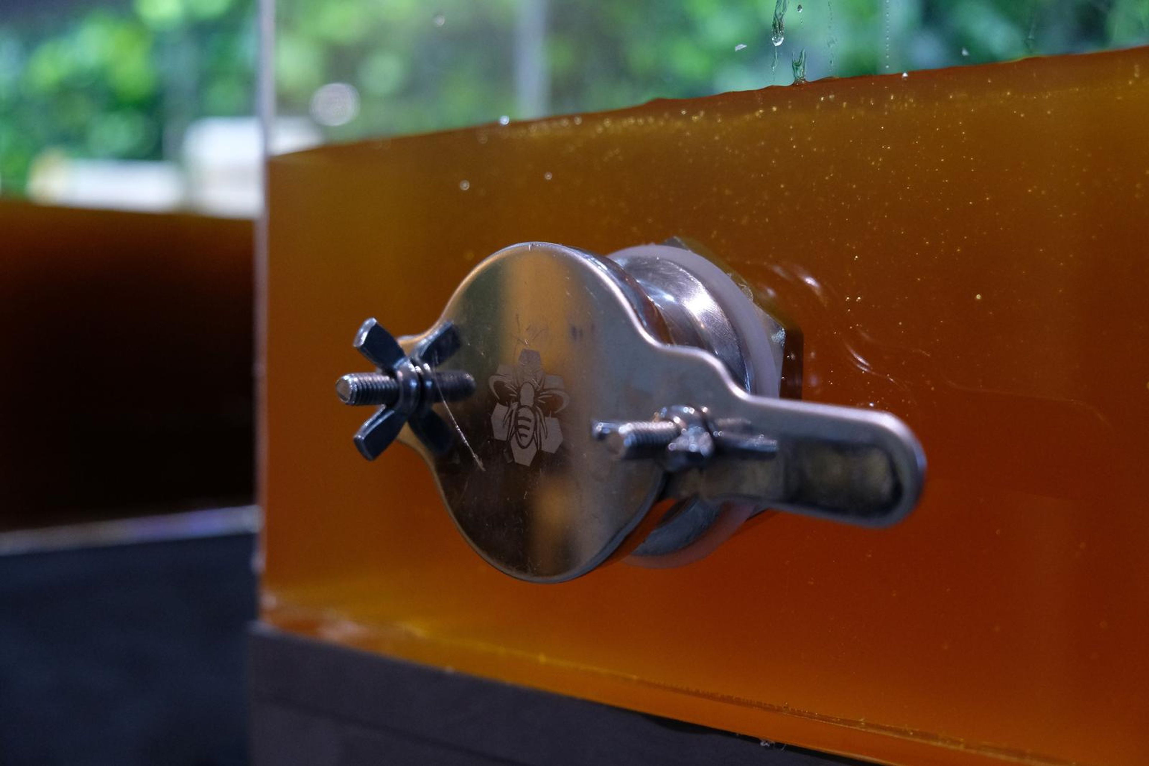 Close-up of a glass dispenser tap with honey inside