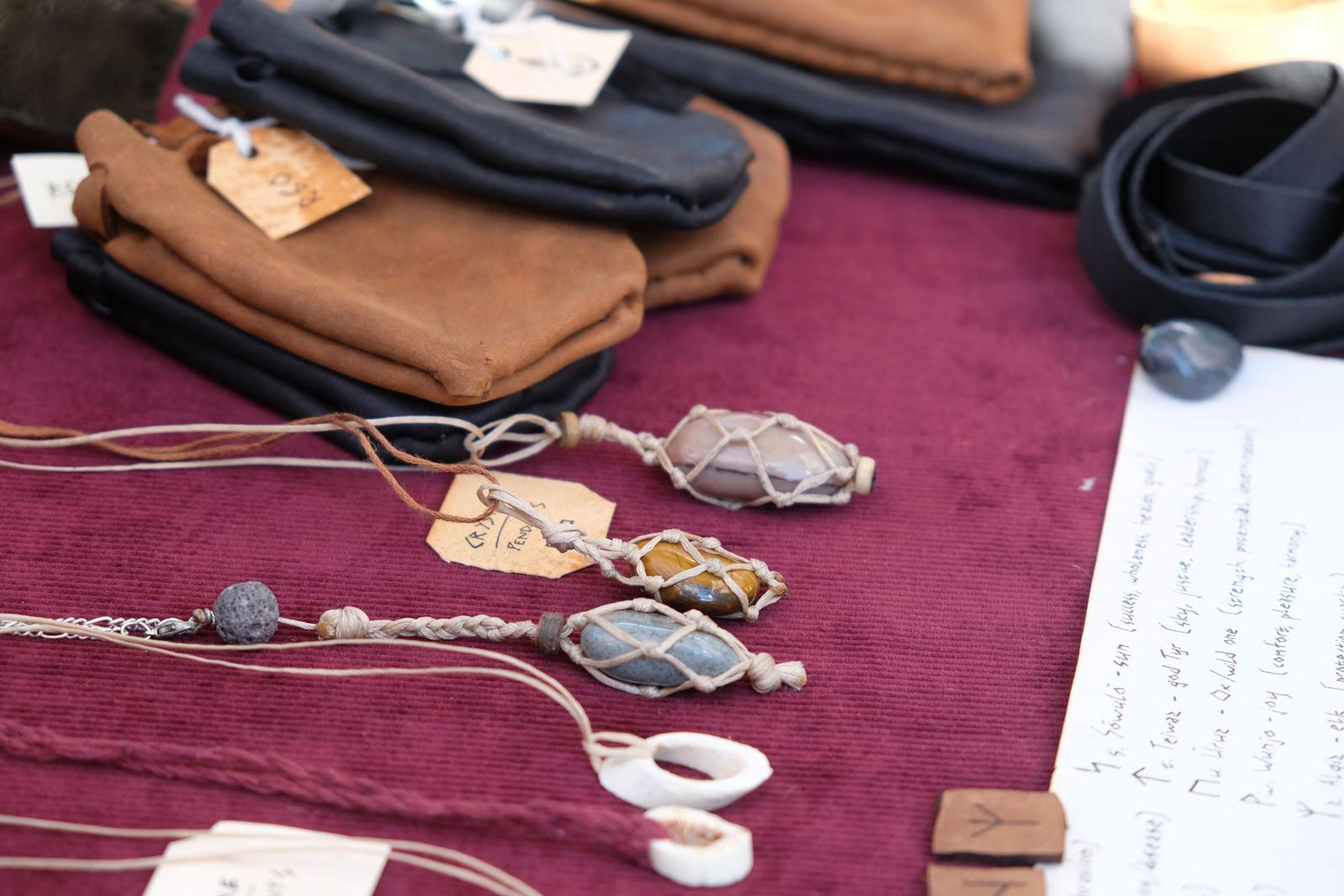 Wire-wrapped crystal and bone pendants with handwritten price tags on maroon cloth